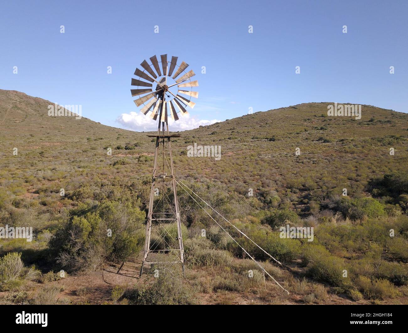 Windmill and water pump in dry landscape Stock Photo