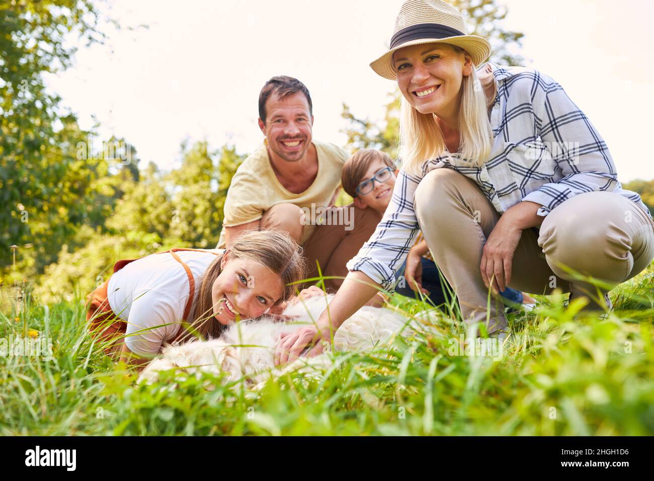 Happy family with two children stroking the dog together in nature Stock Photo