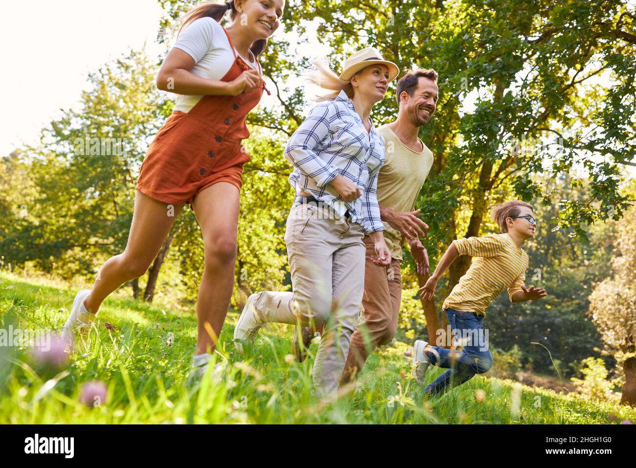 Happy family with daughter and son running in the park on a meadow in summer Stock Photo