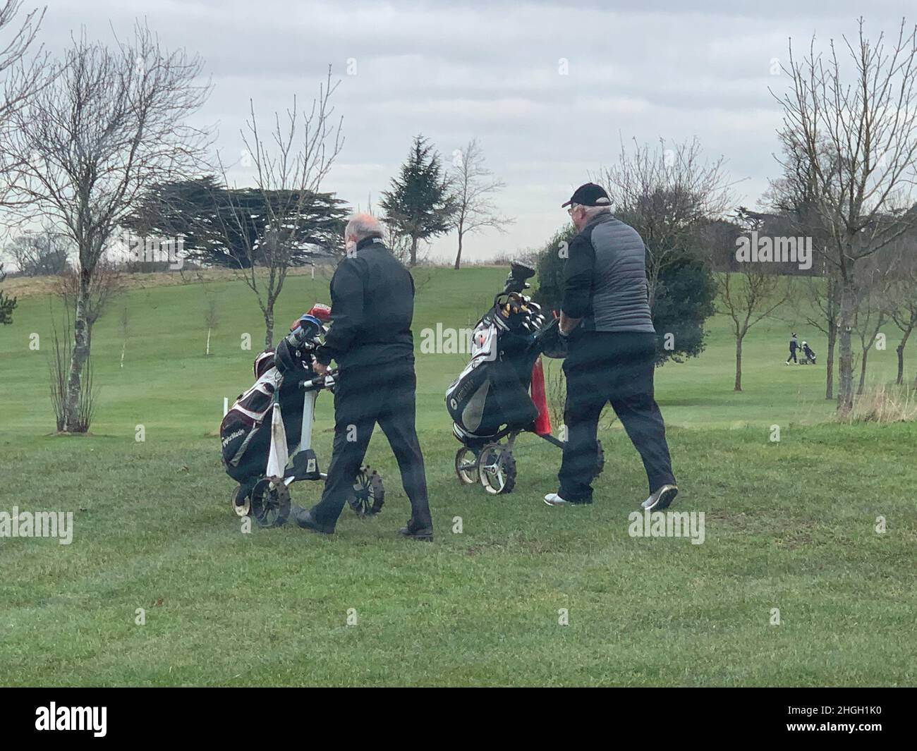 Overstone Golf club Northampton UK play players trolley outside walking bag bags course walk walking grass cap coat caps wheels people person jacket Stock Photo