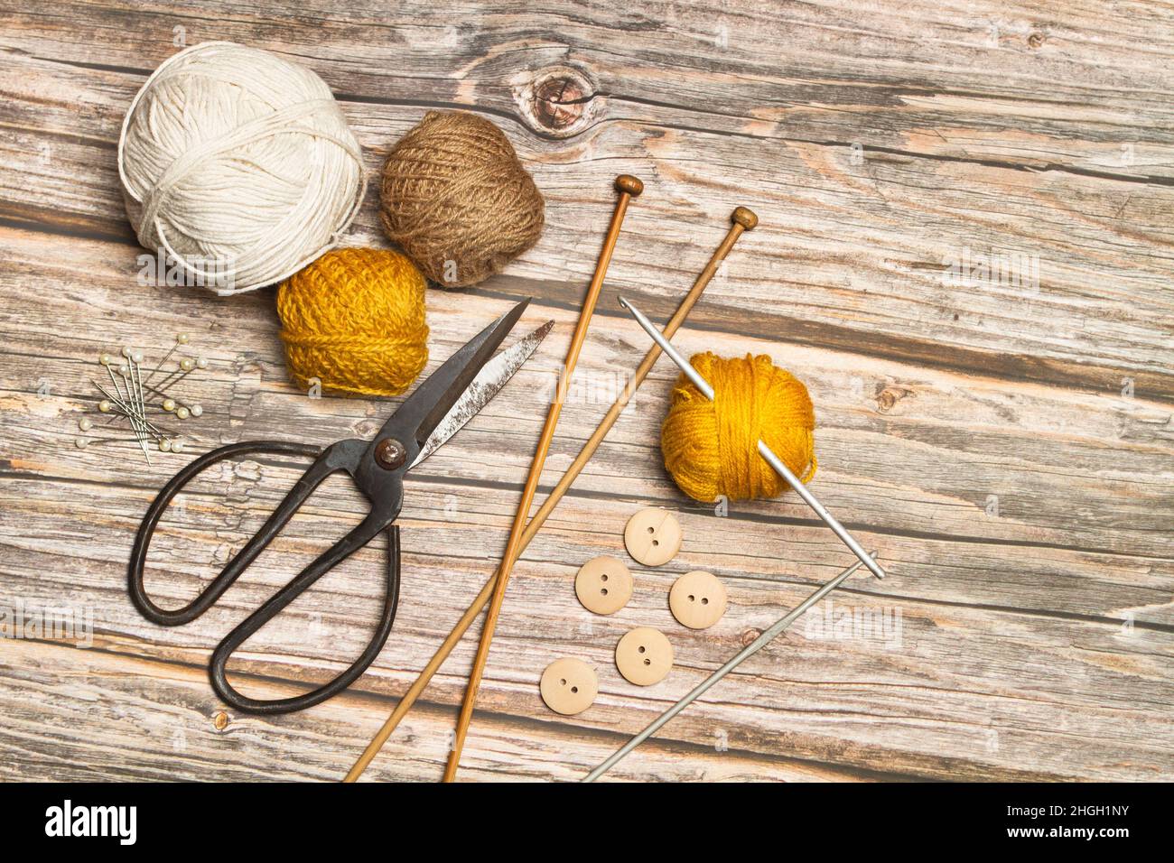 Colored wool spools and crochet hooks on a wooden background with copy space Stock Photo