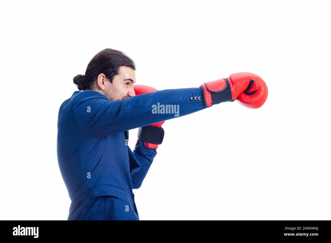 Angry businessman with red boxing gloves, punching with hand, fighting position, clenching teeth. Side view portrait of determined business person kic Stock Photo