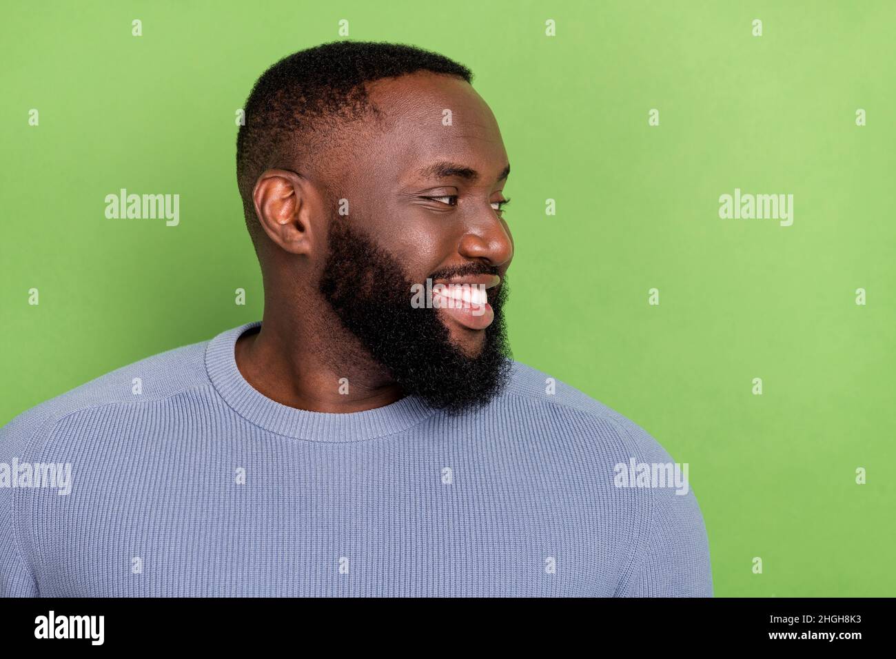 Photo of positive afro guy wear grey pullover looking empty space smiling isolated green color background Stock Photo