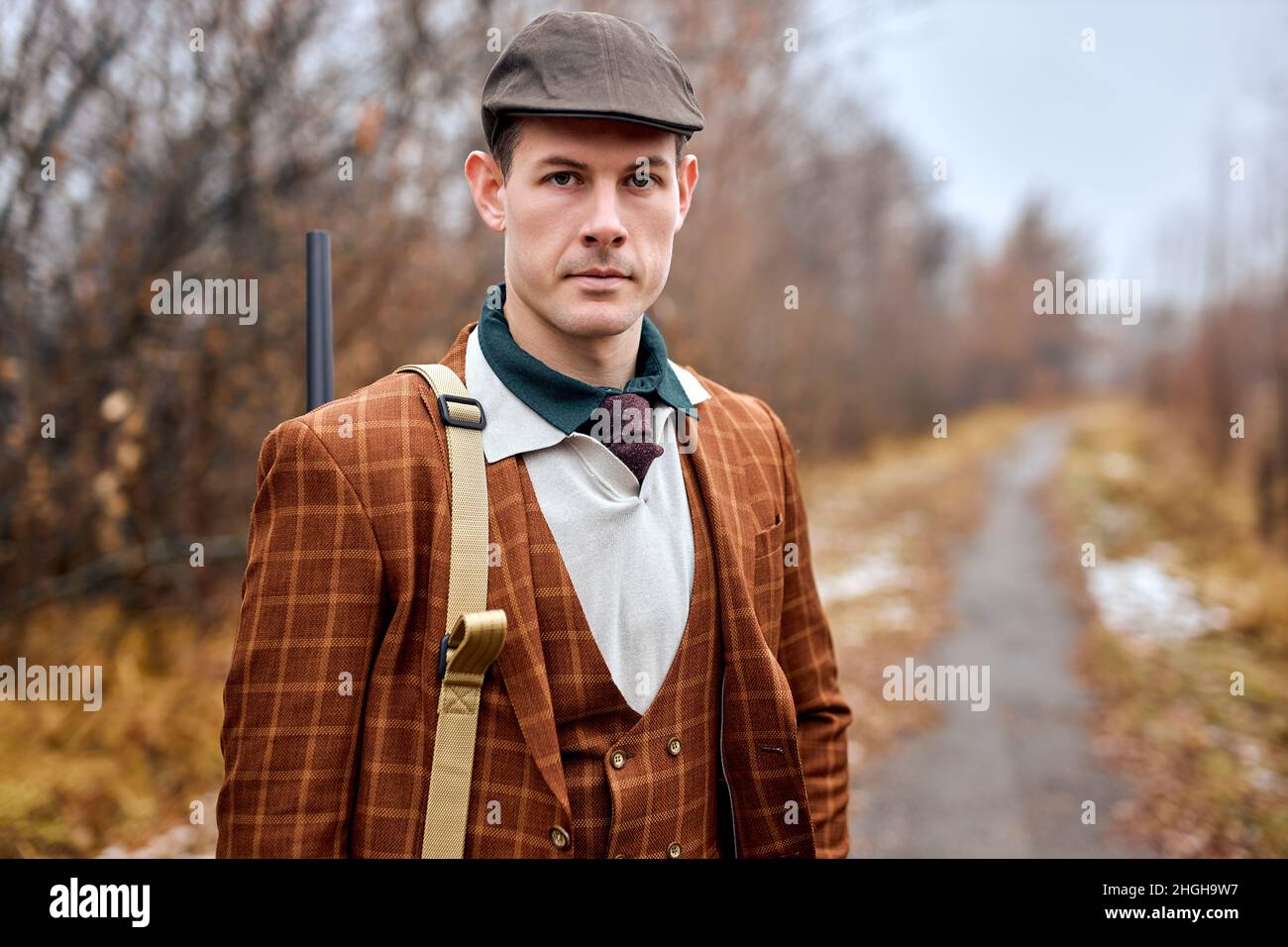 Autumn hunting season. Hunter with shotgun gun on hunt. Autunm hunting. Handsome guy of caucasian appearance in brown classic suit posing looking at c Stock Photo