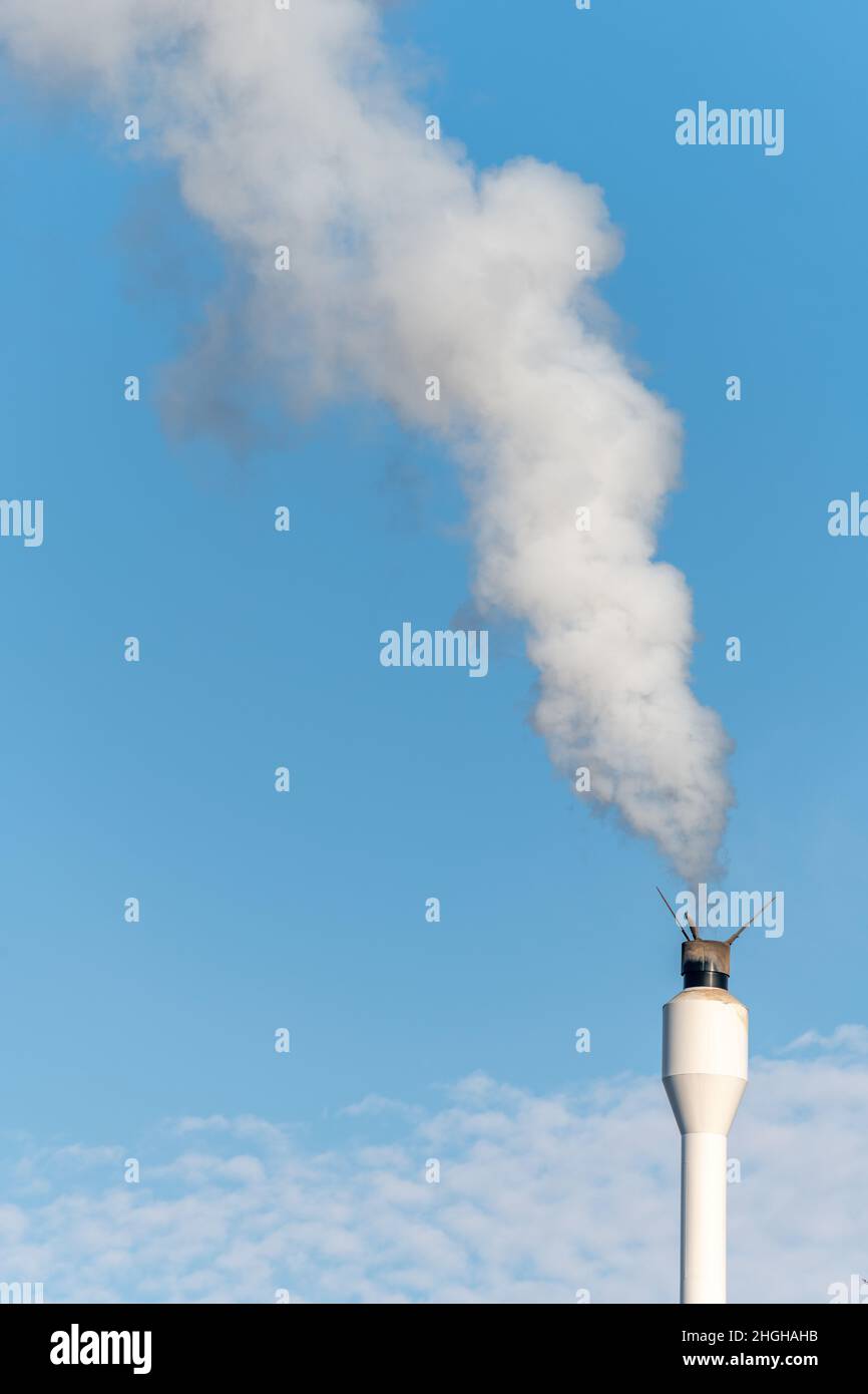 Chimney with a release of white smoke. Wood-fired boiler in a collective dwelling. France. Stock Photo