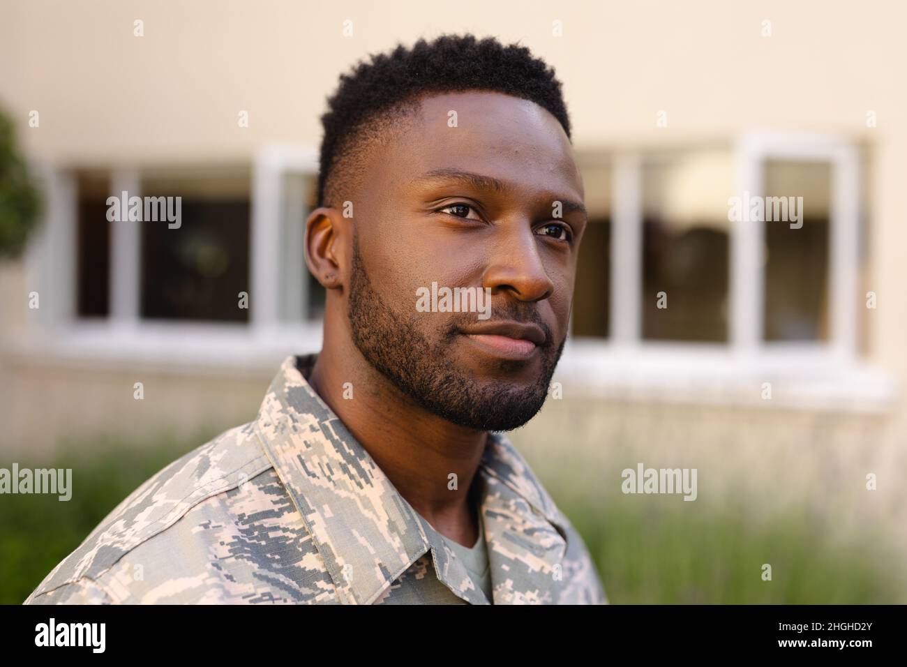 Thoughtful african american army soldier with beard looking away against house Stock Photo