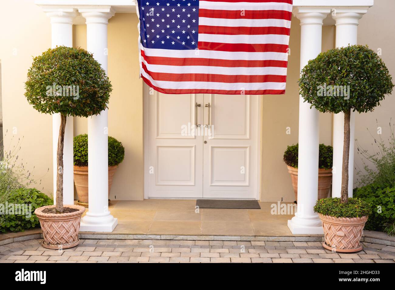 America flag hanging amidst plants at front entrance of house Stock Photo