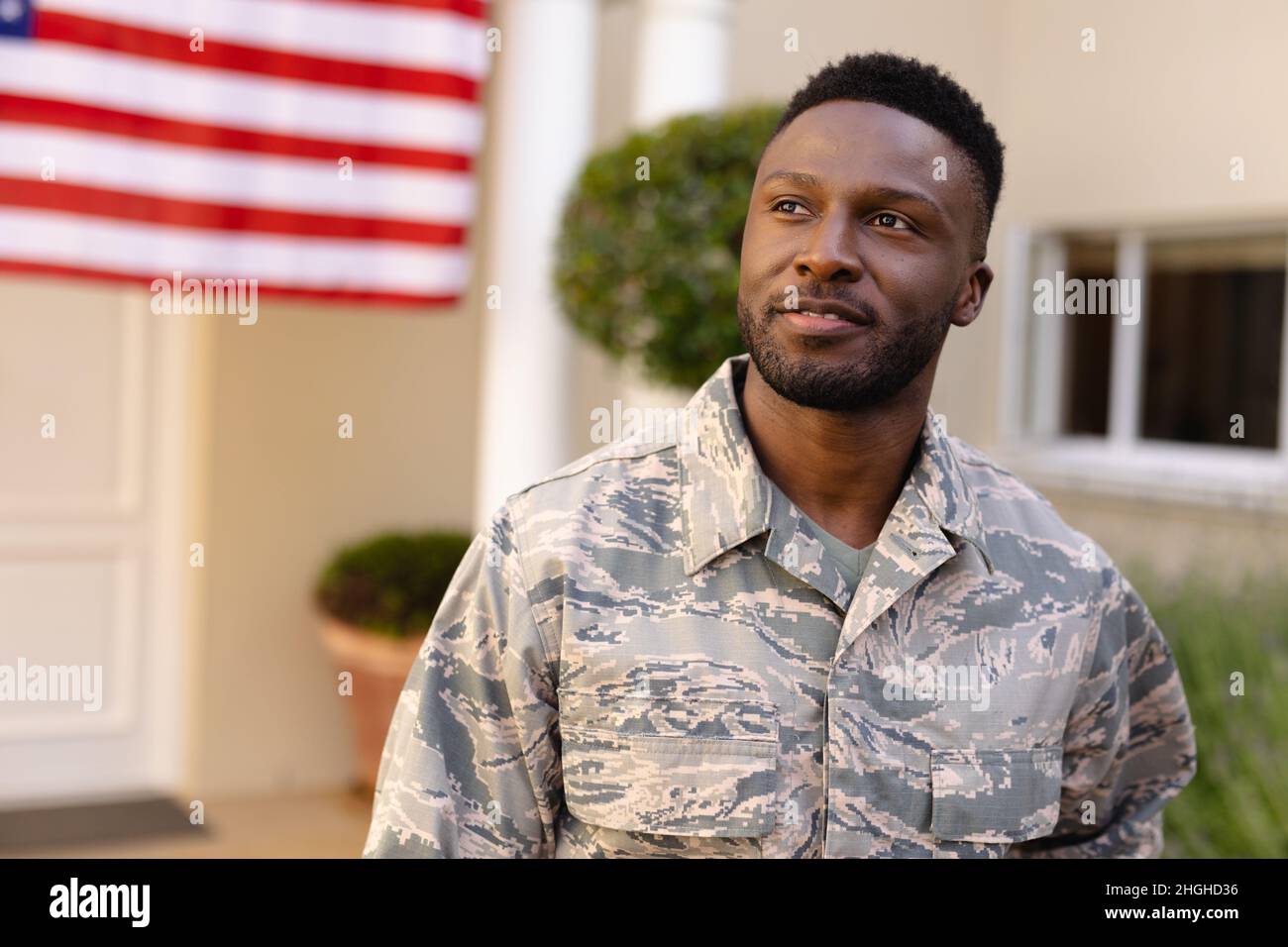 Thoughtful african american army man looking away against house with america flag Stock Photo