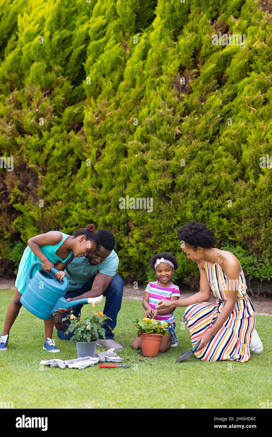 Full length of happy african american family watering plants together ...