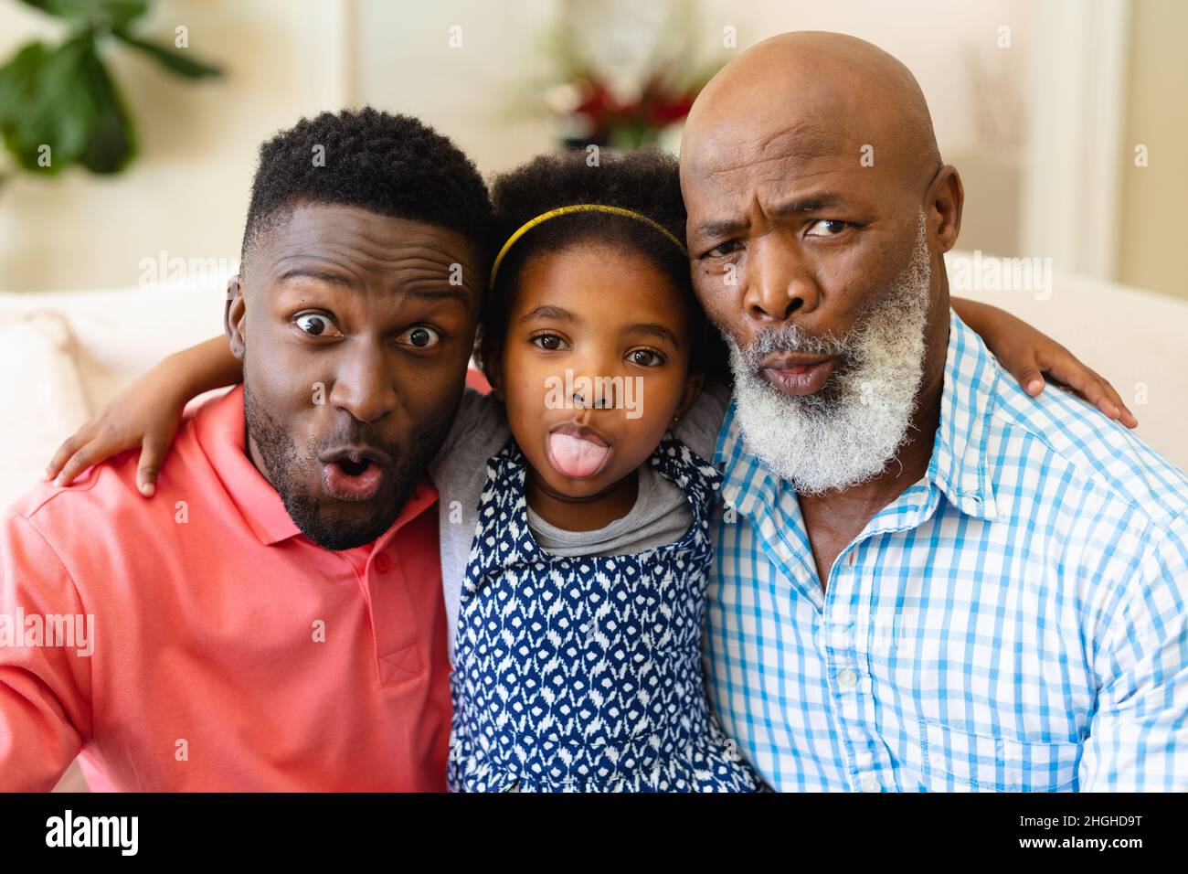 Portrait of african american grandfather, father and granddaughter making silly faces at home Stock Photo