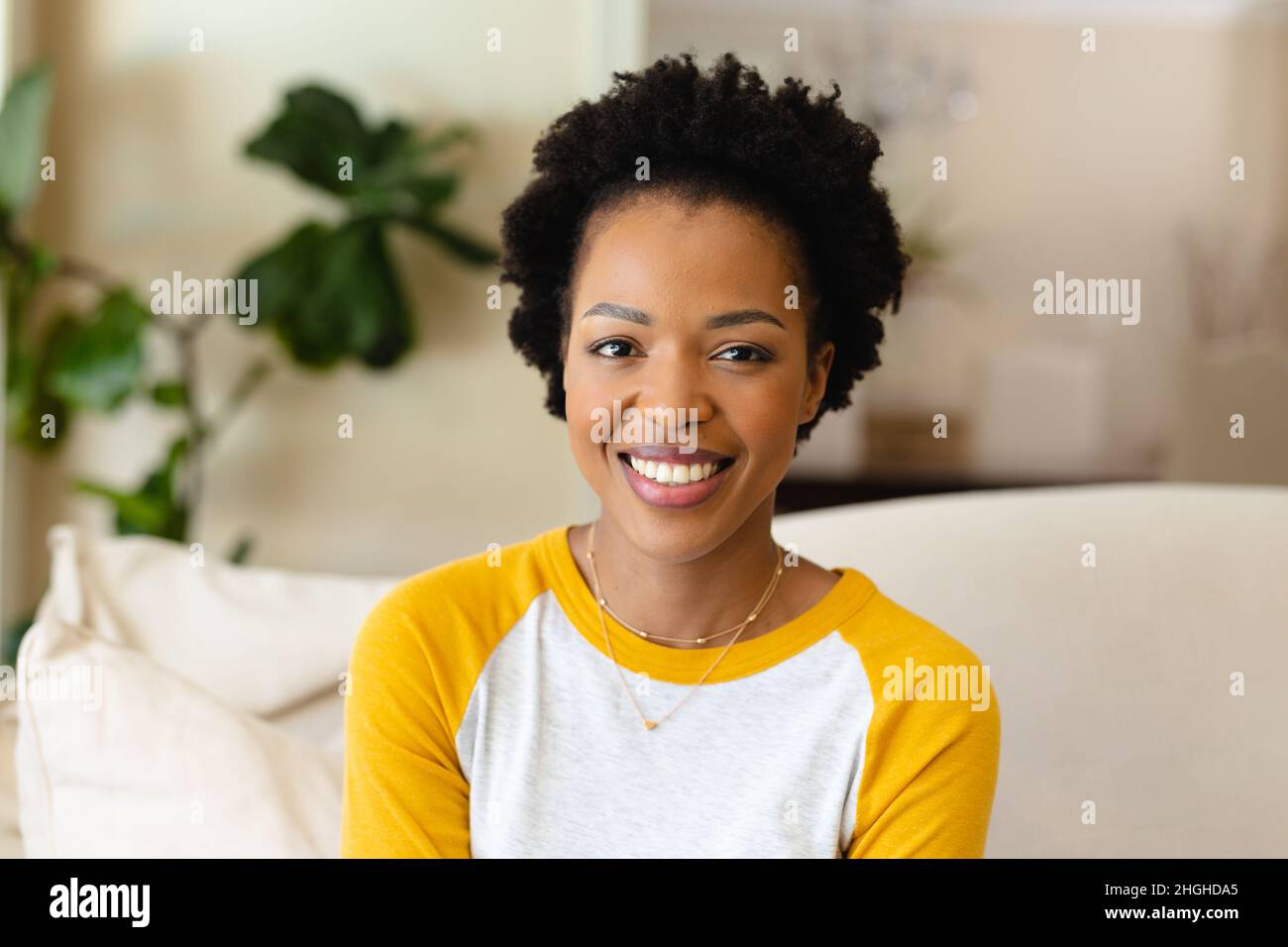 Portrait of african american young woman smiling sitting on the couch ...
