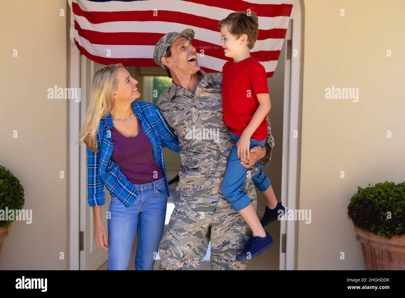 Happy caucasian military man with family standing at house entrance Stock Photo