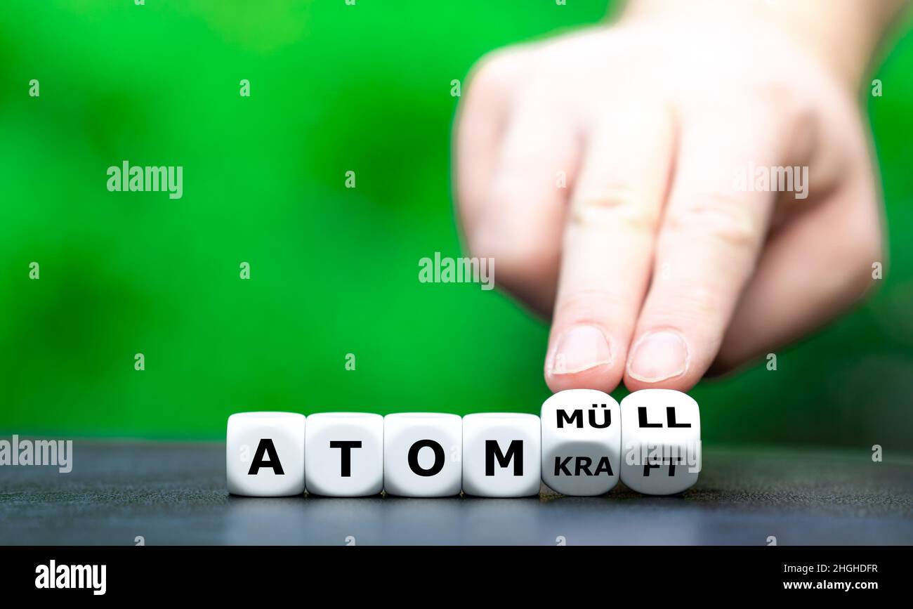 Symbol against nuclear power. Hand turns dice and changes the German expression 'Atomkraft' (nuclear power) to 'Atommuell' (nuclear waste). Stock Photo
