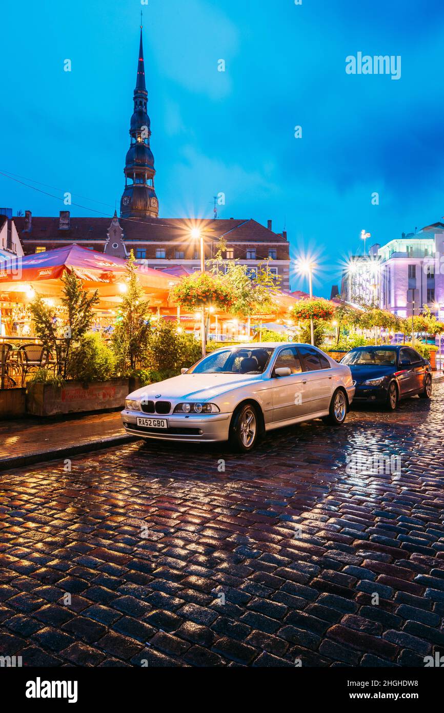 Riga, Latvia. Sedan Car BMW 5 Series E39 Parking Near Open Air Leisure Venue Recreation Center Egle In Evening Or Night Illumination In Old Town On Stock Photo