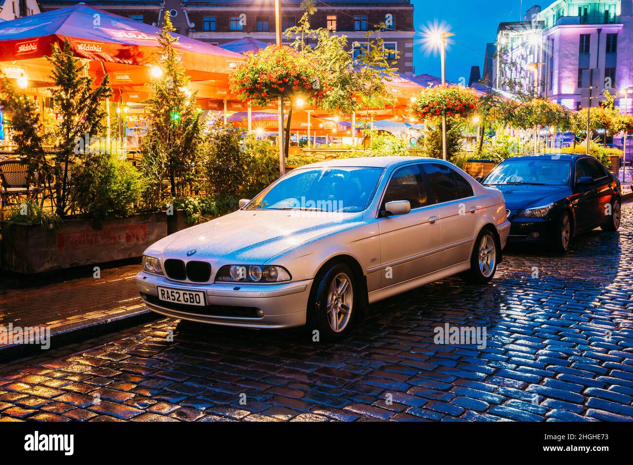 Riga, Latvia. Sedan Car BMW 5 Series E39 Parking Near Street Cafe In Evening Or Night Illumination In Old Town On Kalku Street Stock Photo