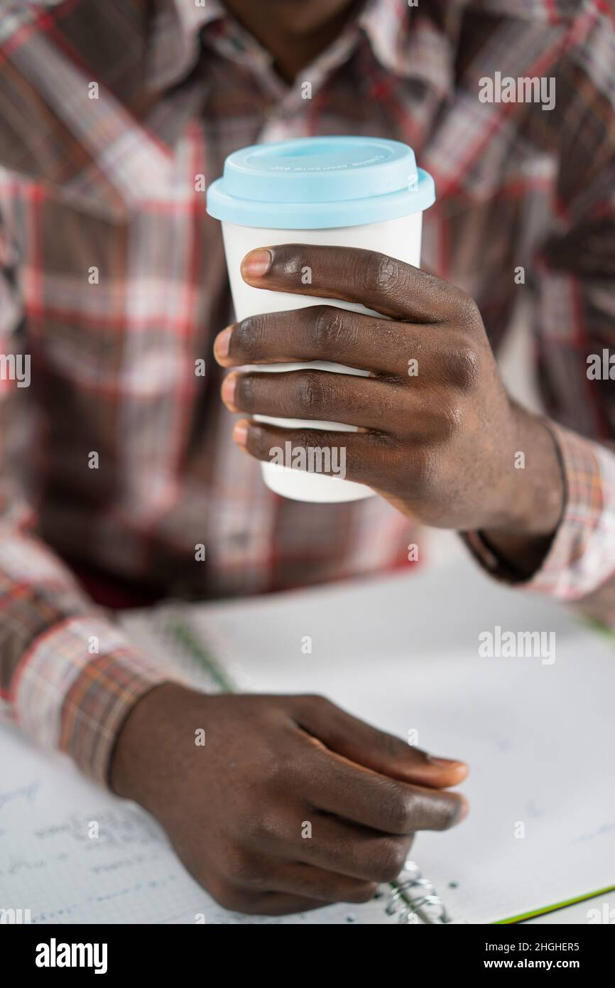 Male Hands Hold a Paper Cup of Coffee. Guy is Having a Disposable Cup of Tea. Morning Coffee, Coffee to Go, Plaid Men's Shirt Background. Close-up. High quality photo Stock Photo