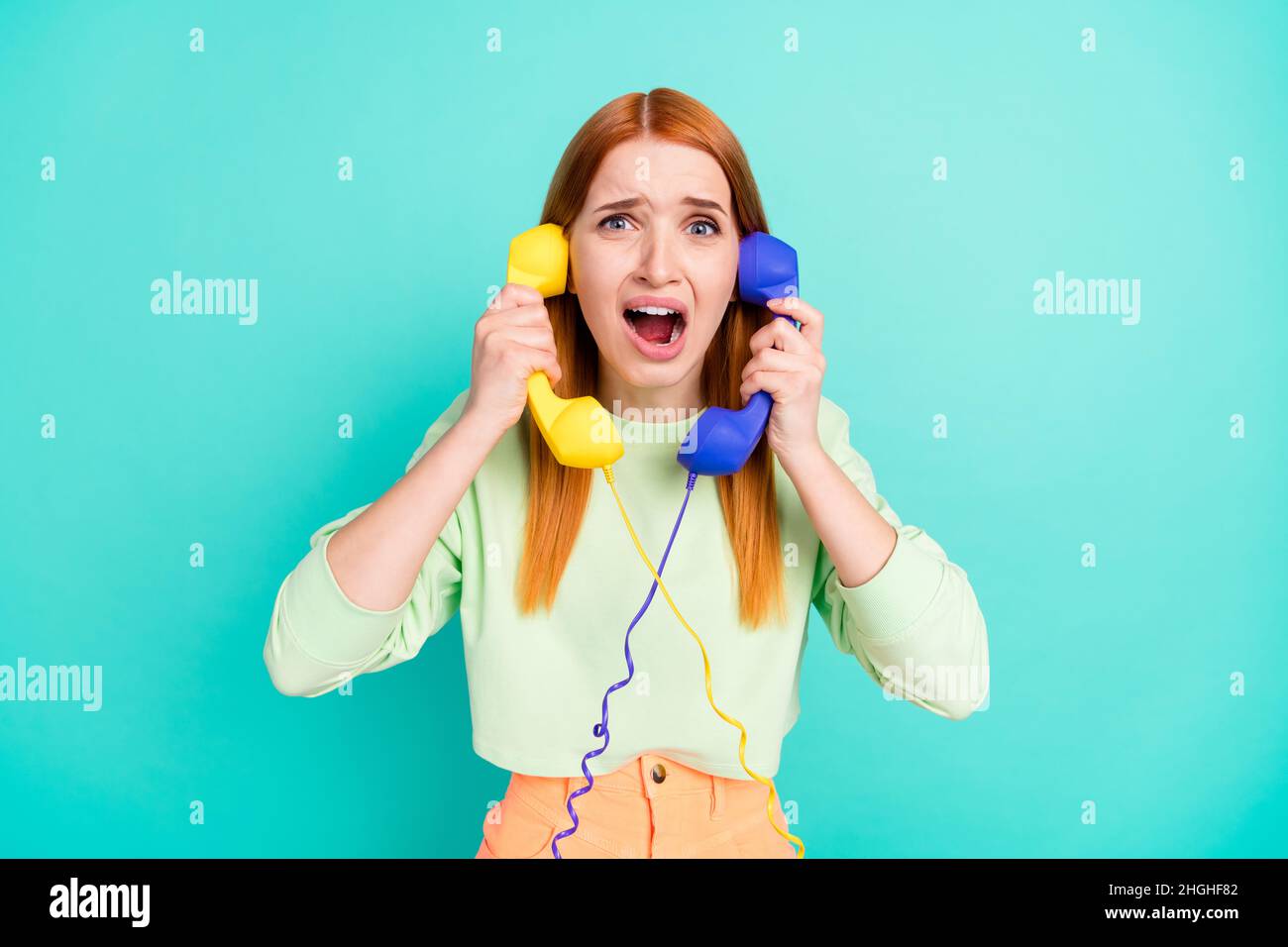 Photo of afraid millennial lady hold phones yell wear sport clothes isolated on vivid teal color background Stock Photo