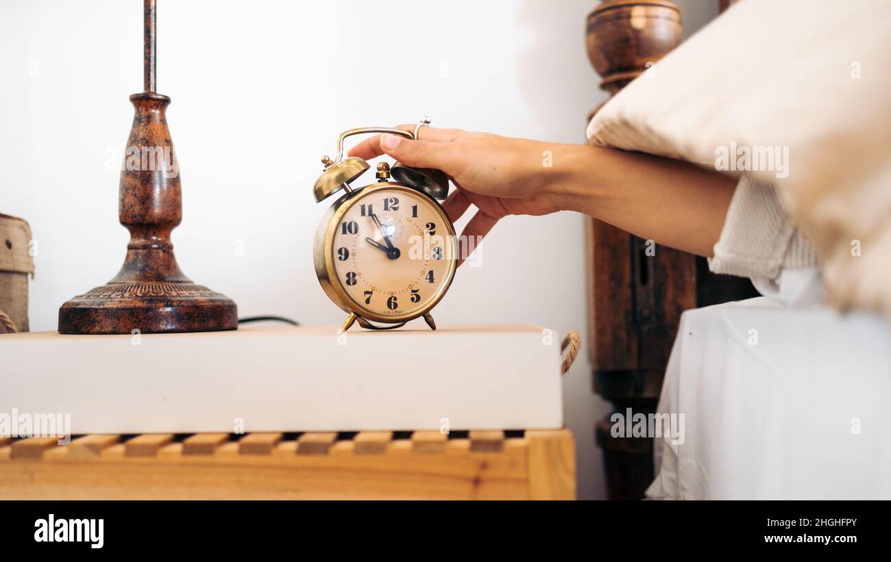 Hand of an unrecognizable young woman turning off a vintage alarm clock in  the morning Stock Photo - Alamy, image size:1300x821
