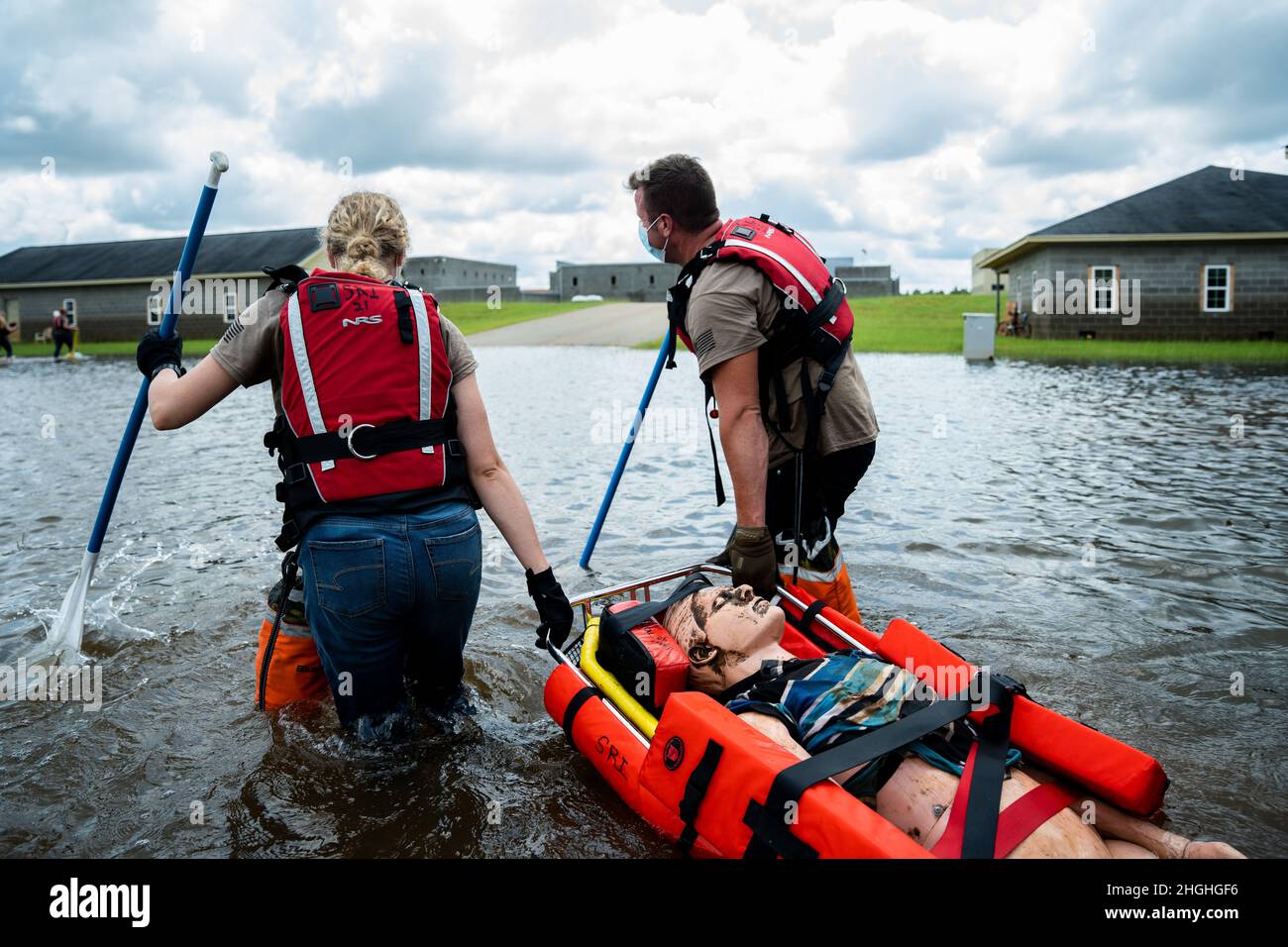 Staff Sgt. Bailey Clark (left) and Capt. Aaron Cohlima (right), 139th Medical Group, carry a backboard through the water during urban search and rescue training at the Guardian Centers, Perry, Georgia, Aug. 3, 2021. The Airmen applied life-saving skills in various disaster simulations. Stock Photo