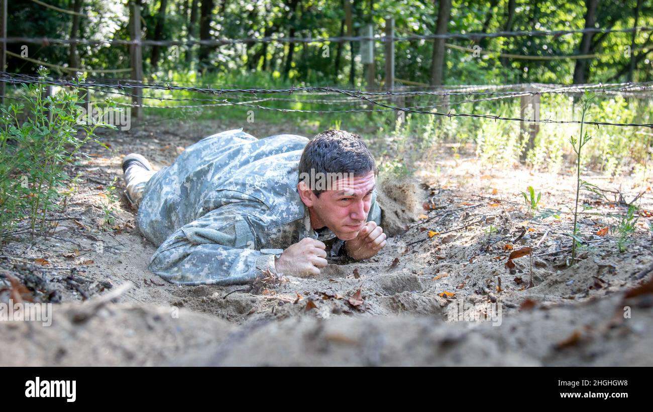 U.S. Army Spc. Ben Skelton, Headquarters and Headquarters Company, 46th Military Police Command, Michigan Army National Guard, low crawls under the belly crawl obstacle at the Confidence Course at Fort Custer Training Center, Augusta, Michigan, August 3, 2021. Western Michigan University’s Reserve Officer Training Corps and the Michigan Army National Guard partnered to host a three-day summer camp for 30 participants. Stock Photo