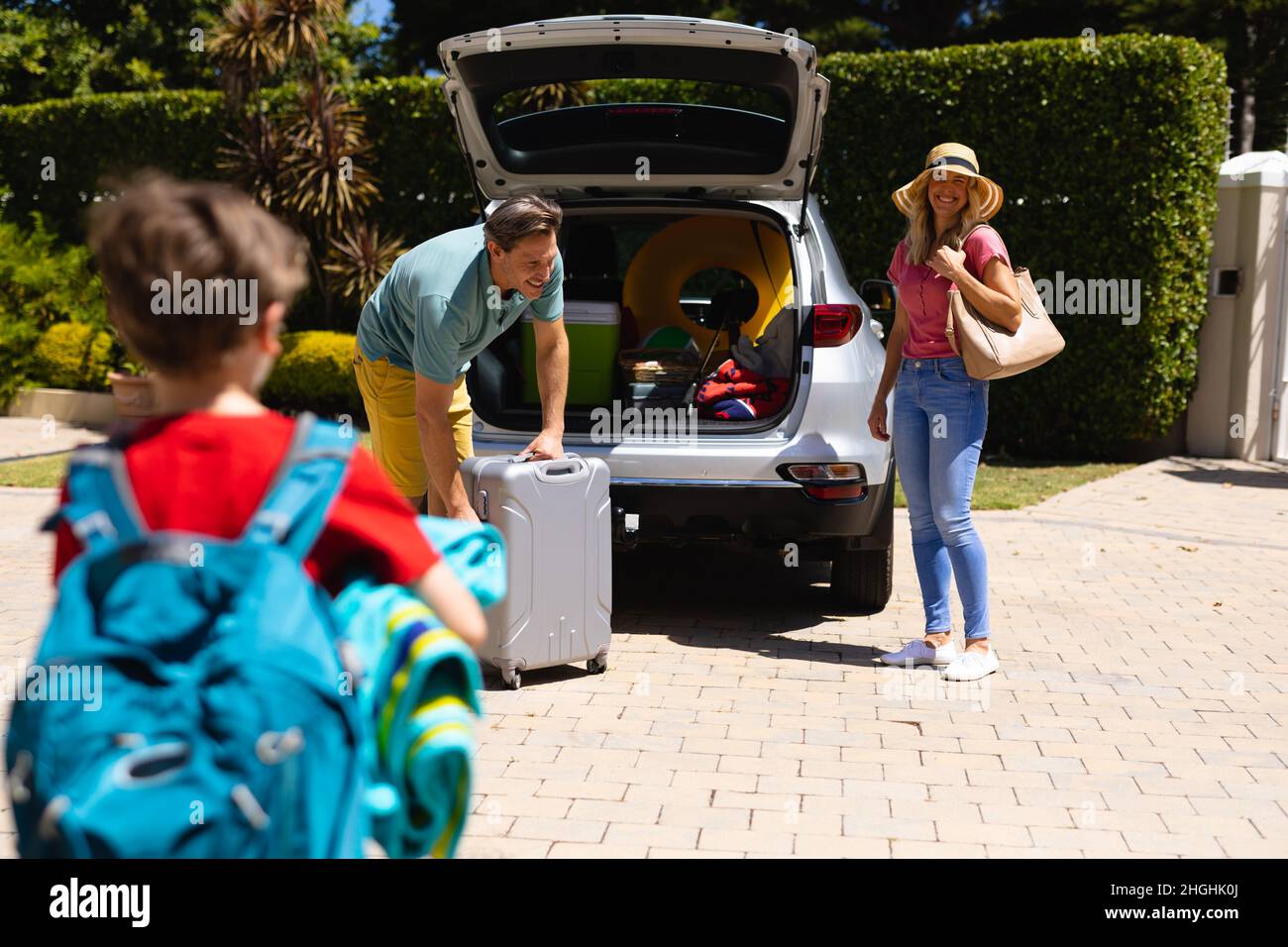Happy caucasian family putting their luggage in their car outdoors Stock Photo