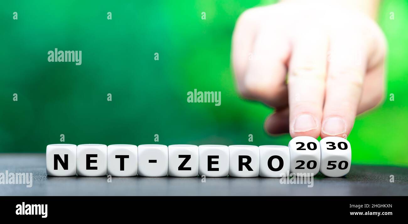 Hand turns dice and changes the expression 'net-zero 2050' to 'net-tero 2030'. Stock Photo