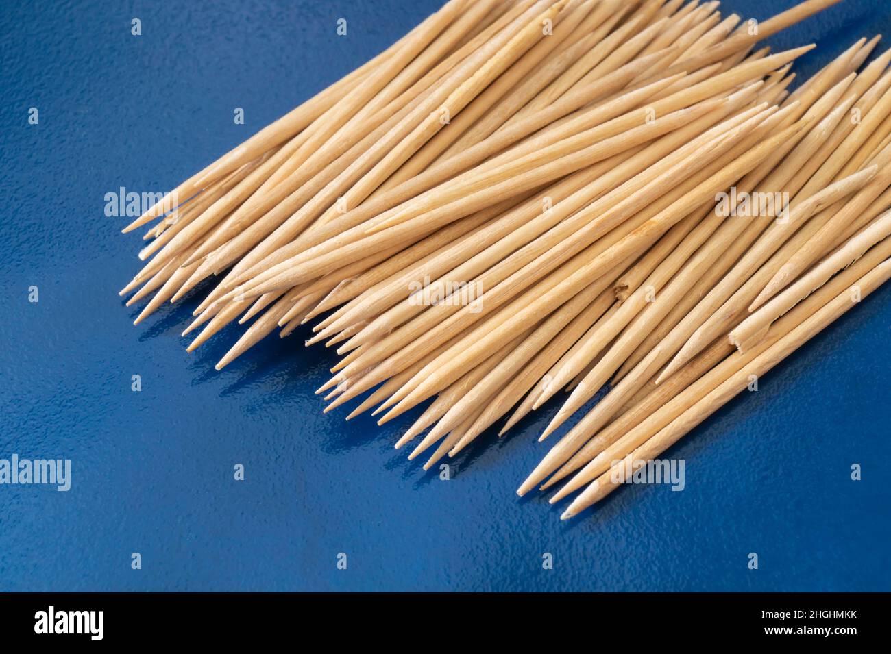 Wooden toothpicks on a blue background. A sharp object for brushing teeth Stock Photo