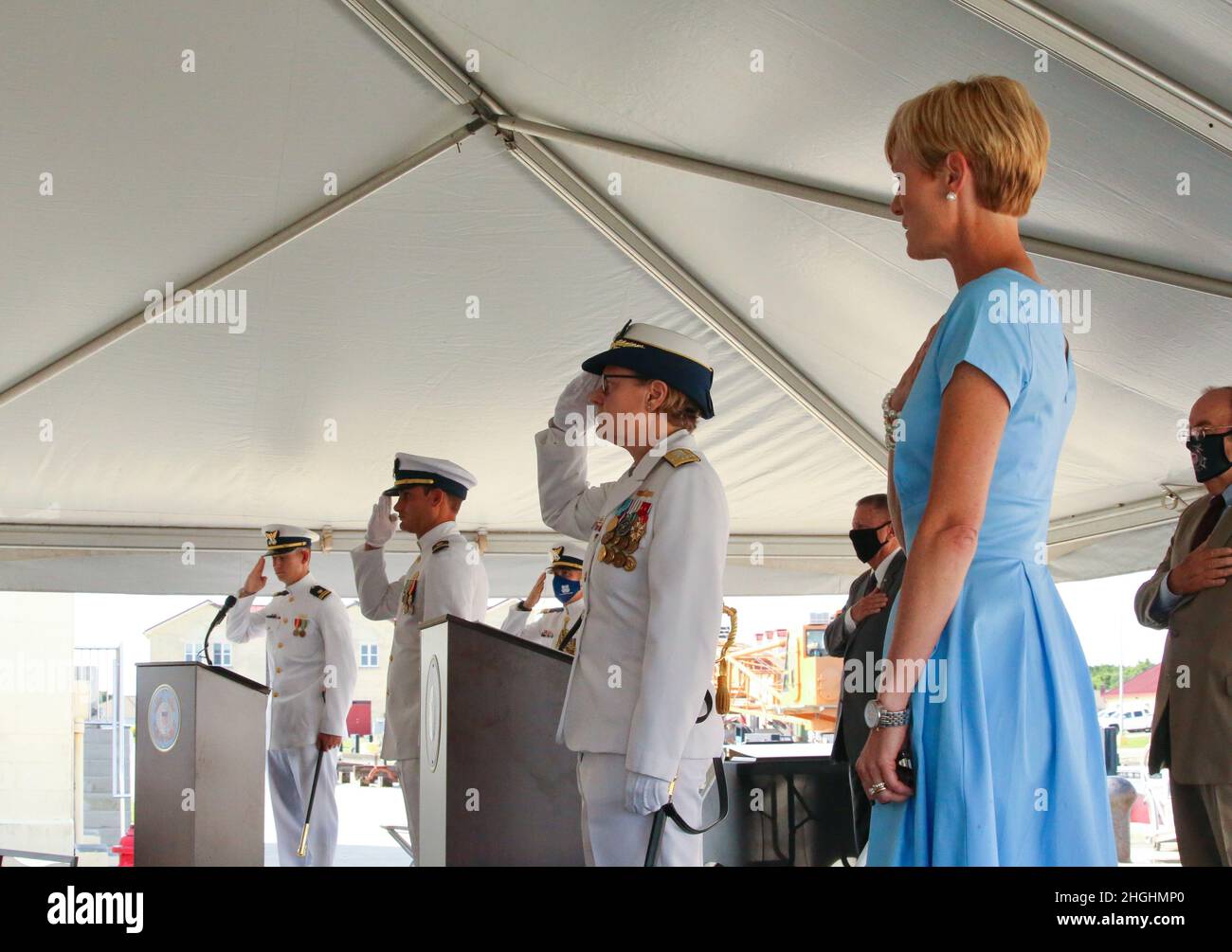 Members stand for the national anthem during the Coast Guard Cutter Glen Harris commissioning ceremony at Coast Guard Sector Field Office Fort Macon in Beaufort, North Carolina, Aug. 6, 2021. The cutter's namesake, Chief Petty Officer Glen Livingston Harris, acted as a landing craft coxswain during the landing of Tulagi, Aug. 7-9, 1942, during World War II. Along with three other U.S. Coast Guard coxswains, Harris landed the first U.S. Marines on Tulagi and, over the next three days of conflict, made repeated trips under heavy enemy fire to deliver ammunition and other supplies to U.S. forces. Stock Photo