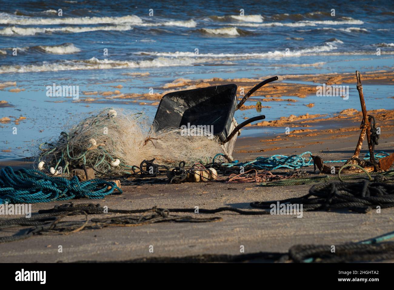 Fishing net, ropes, cart, and anchor on the sand near the ocean at Guaratiba Beach, Prado, Bahia, Brazil. Stock Photo