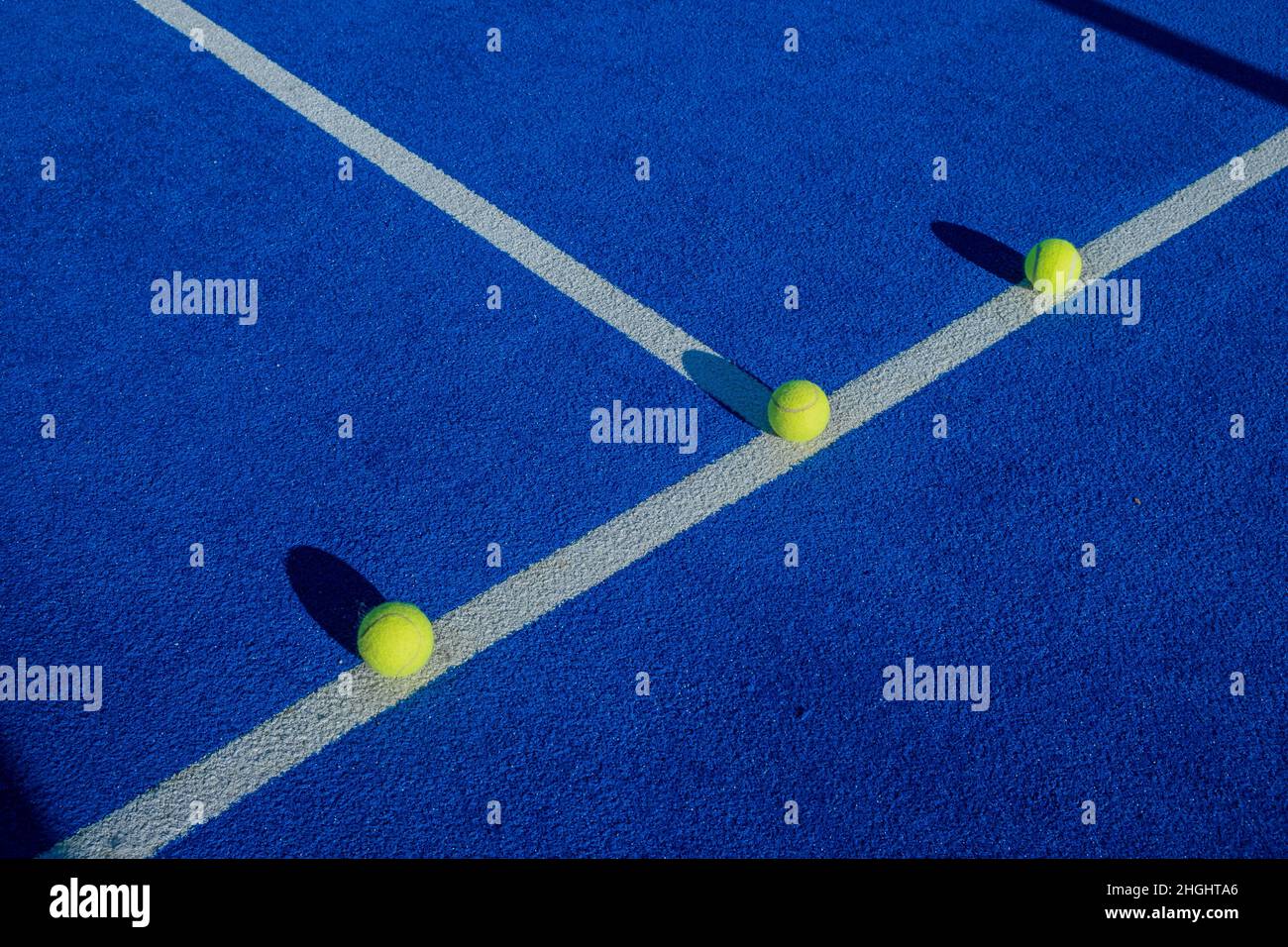 Racket sports. Three paddle tennis balls on the line of a blue paddle tennis court Stock Photo