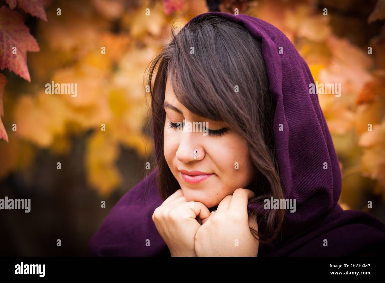 Outdoor portrait of beautiful young woman and colorful autumn leaf, portrait of beautiful young woman with piercing Stock Photo