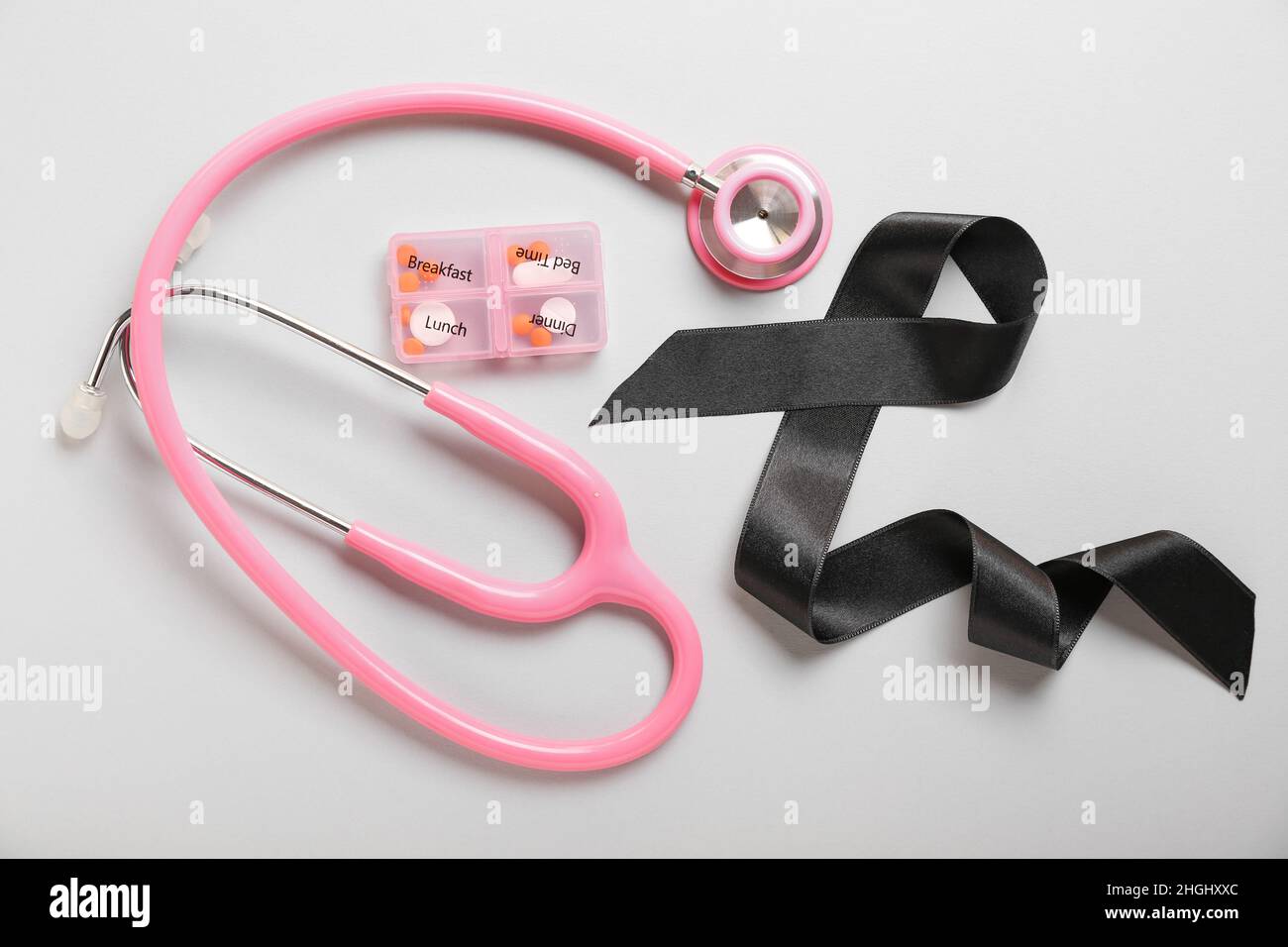 Black ribbon, stethoscope and pills on grey background. Melanoma ...