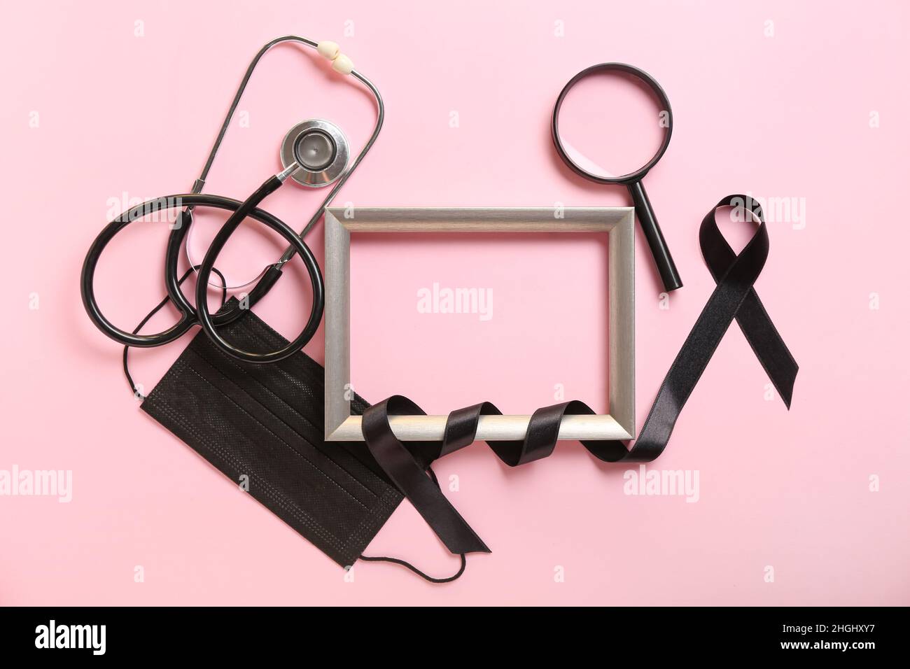 Frame with black ribbon, stethoscope and magnifier on color background ...