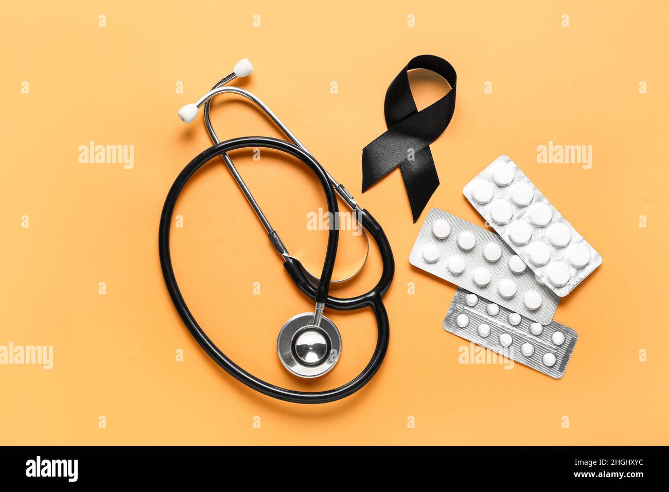 Black ribbon, stethoscope and pills on orange background. Melanoma ...