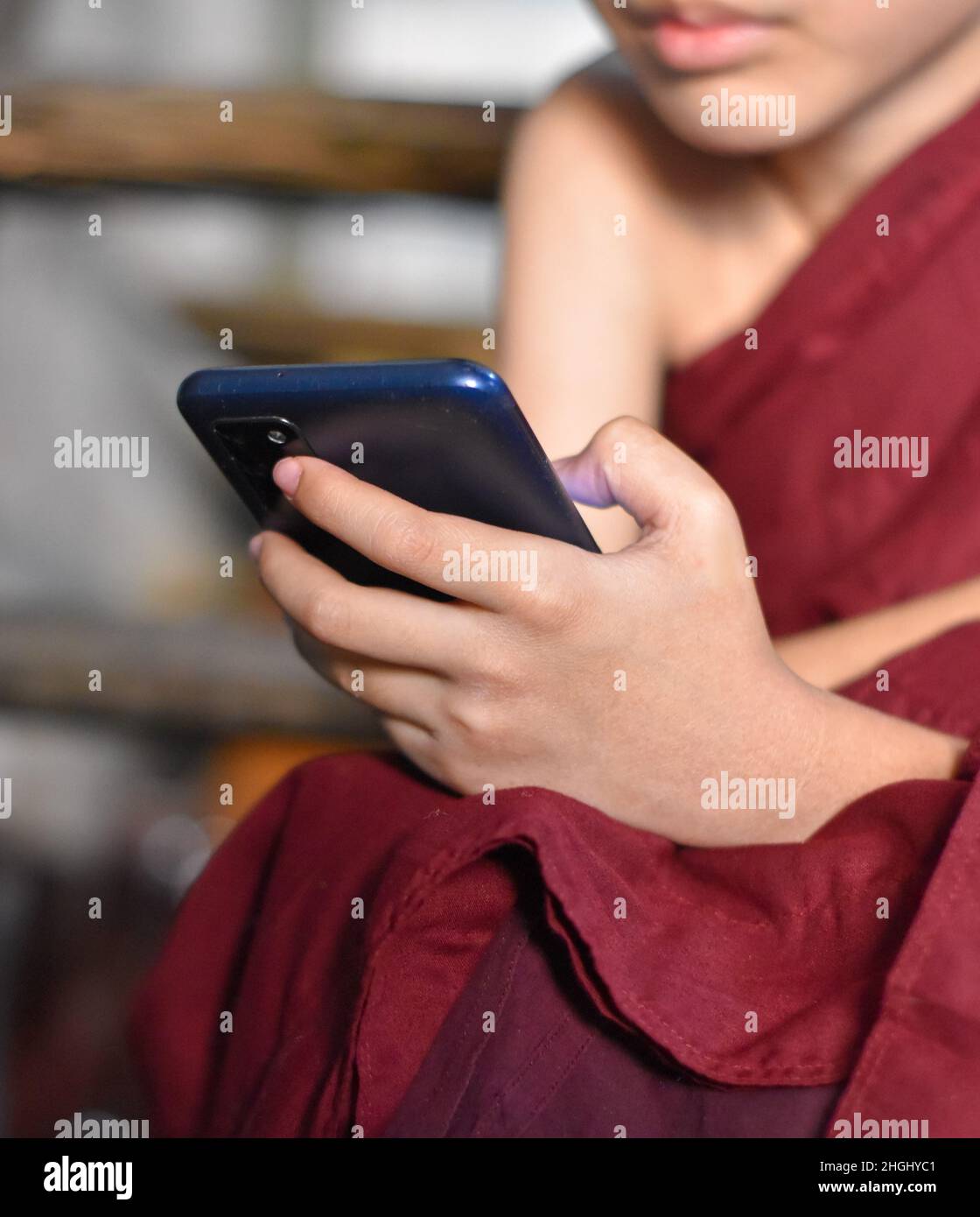 Asian, Myanmar little monk watching mobile smart phone. Concept of screen time. Stock Photo