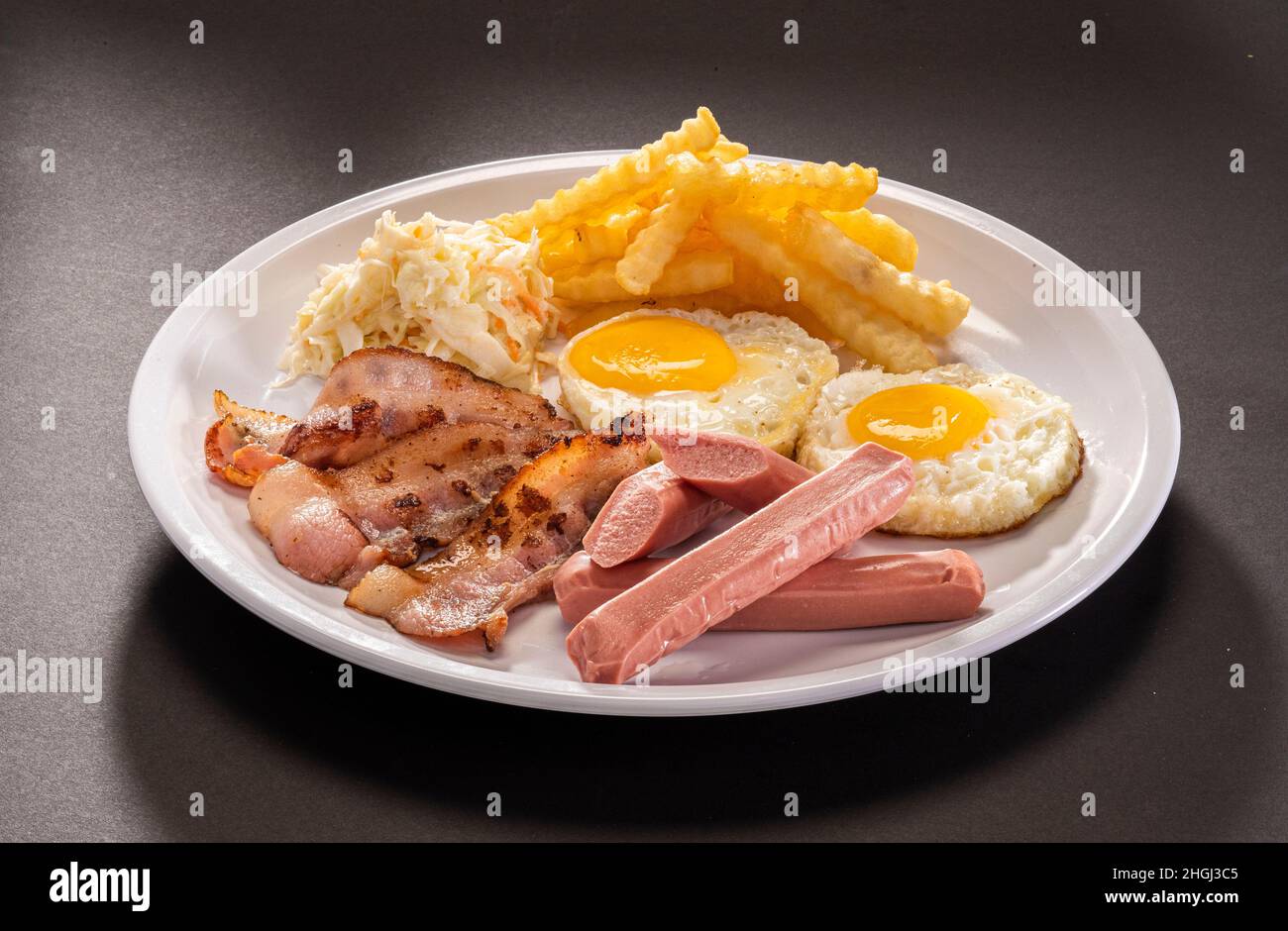 English breakfast set with eggs, pork slice, french fries and mushrooms in white plate Stock