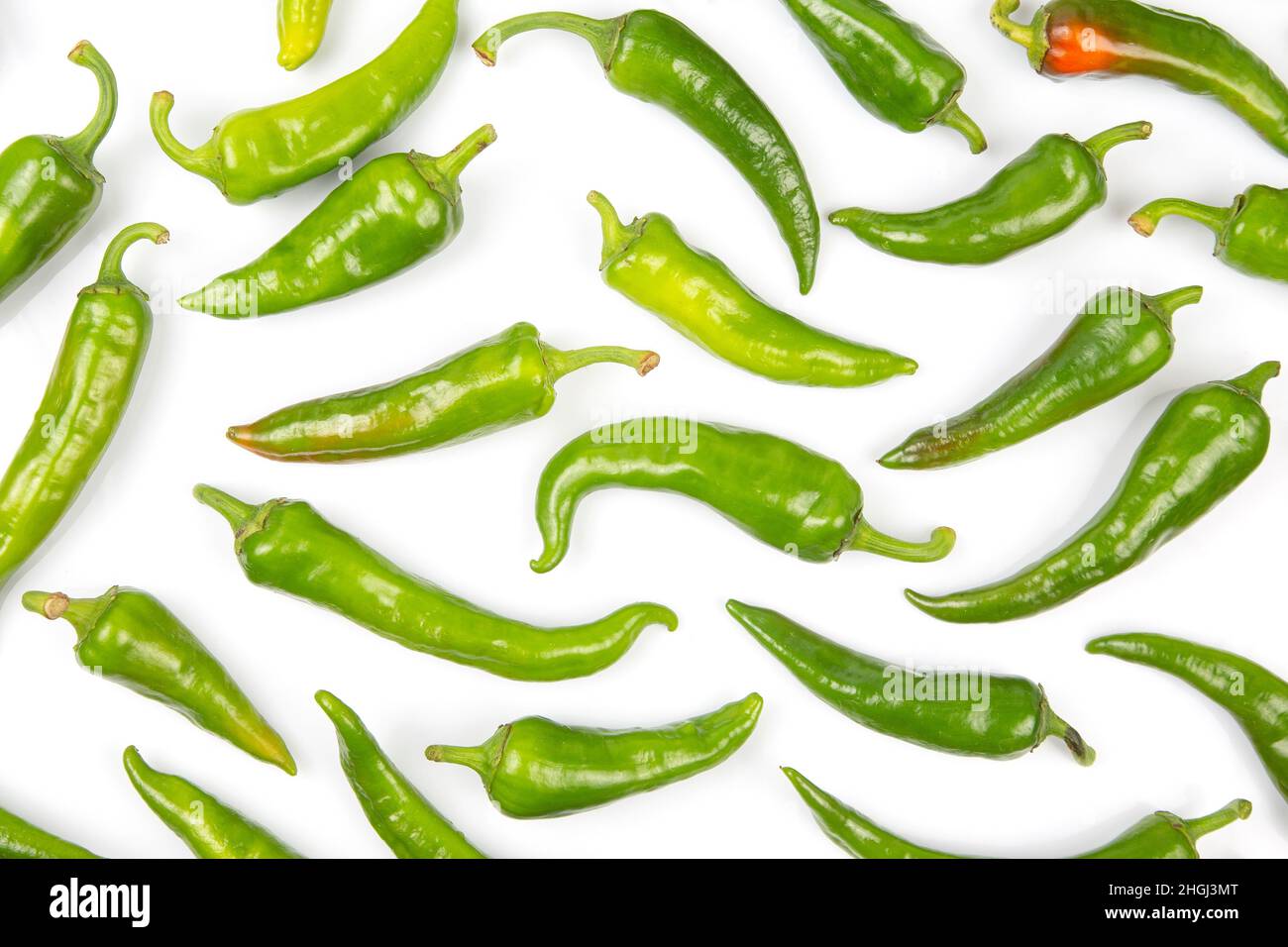 green hot peppers evenly spread on a white background. vitamin