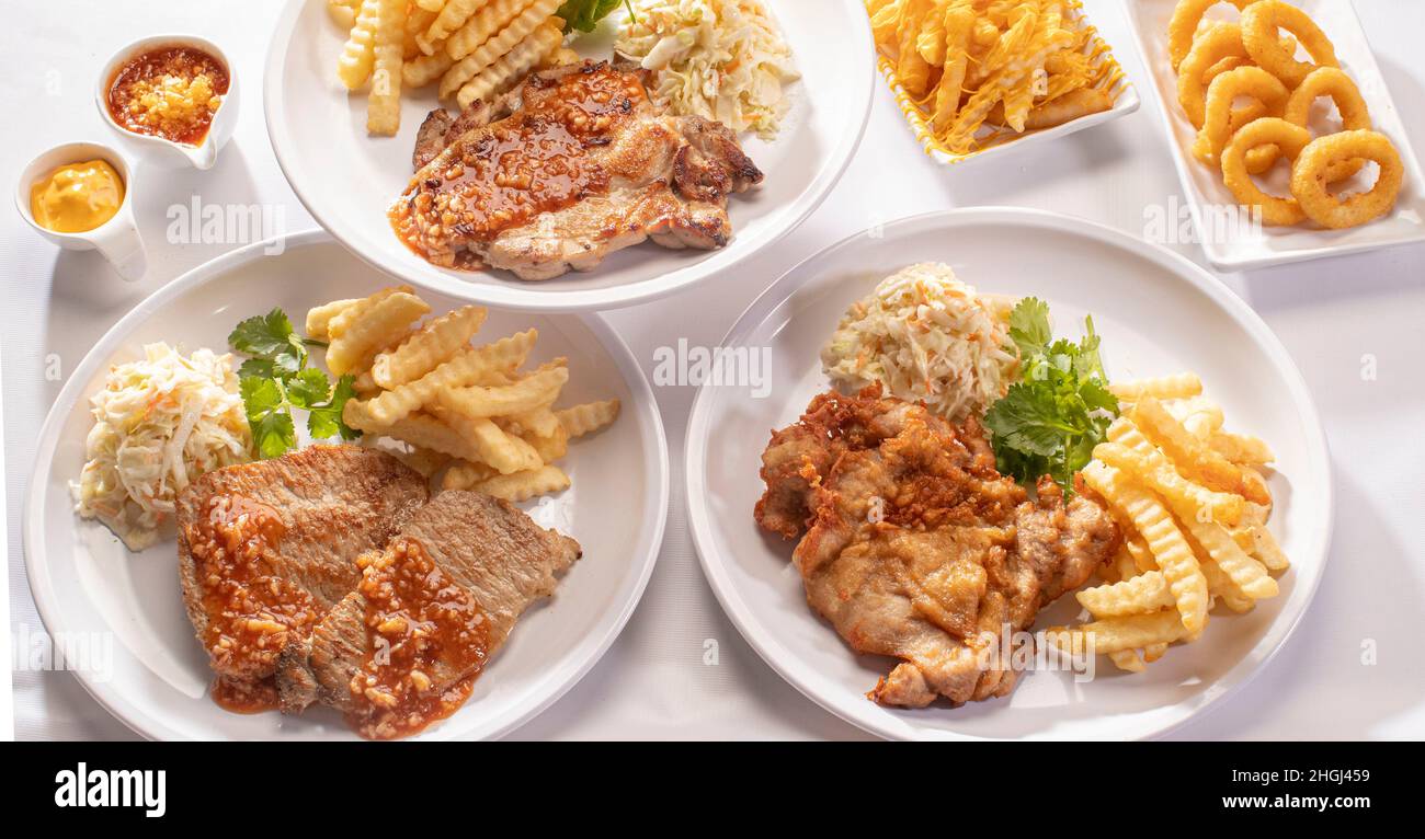 Mixed grill food set full table Sirloin Steak, pork chop, Grilled Lamb Chop, chicken cutlet, chicken chop, Cheese Fries Drizzle, onion rings, french f Stock Photo