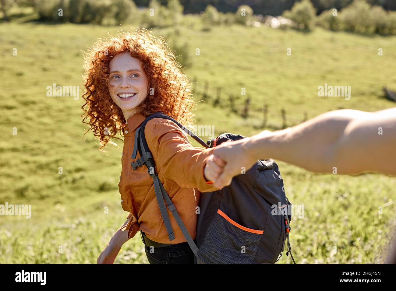 Follow me. Redhead curly woman takes man's hand, leads in the forest to ...
