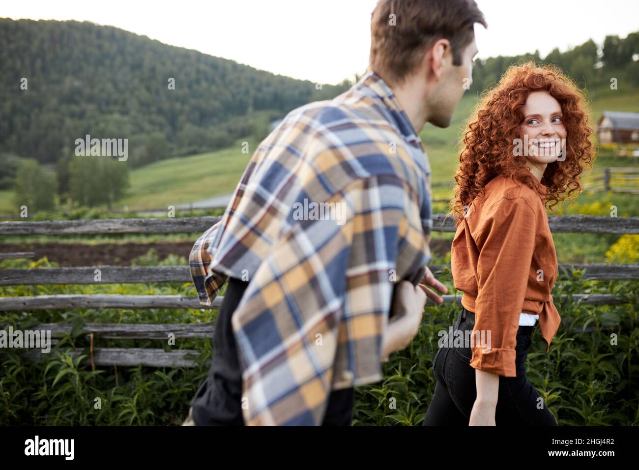 Happy couple walking in countryside in the evening, redhead curly lady ...