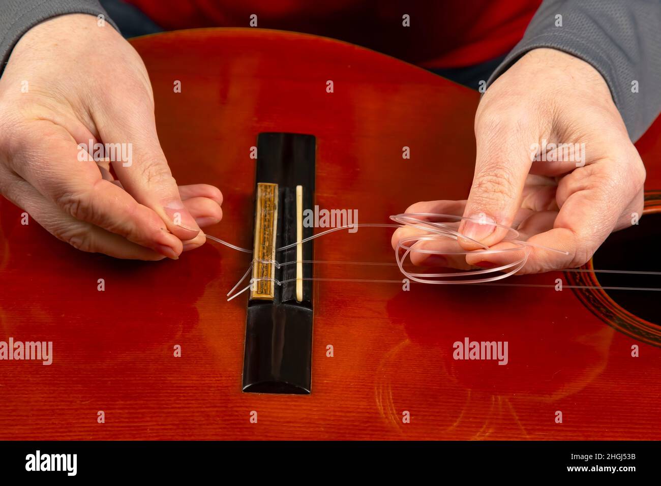 replacement and insertion of nylon strings in a classical guitar. lesson for a musician Stock