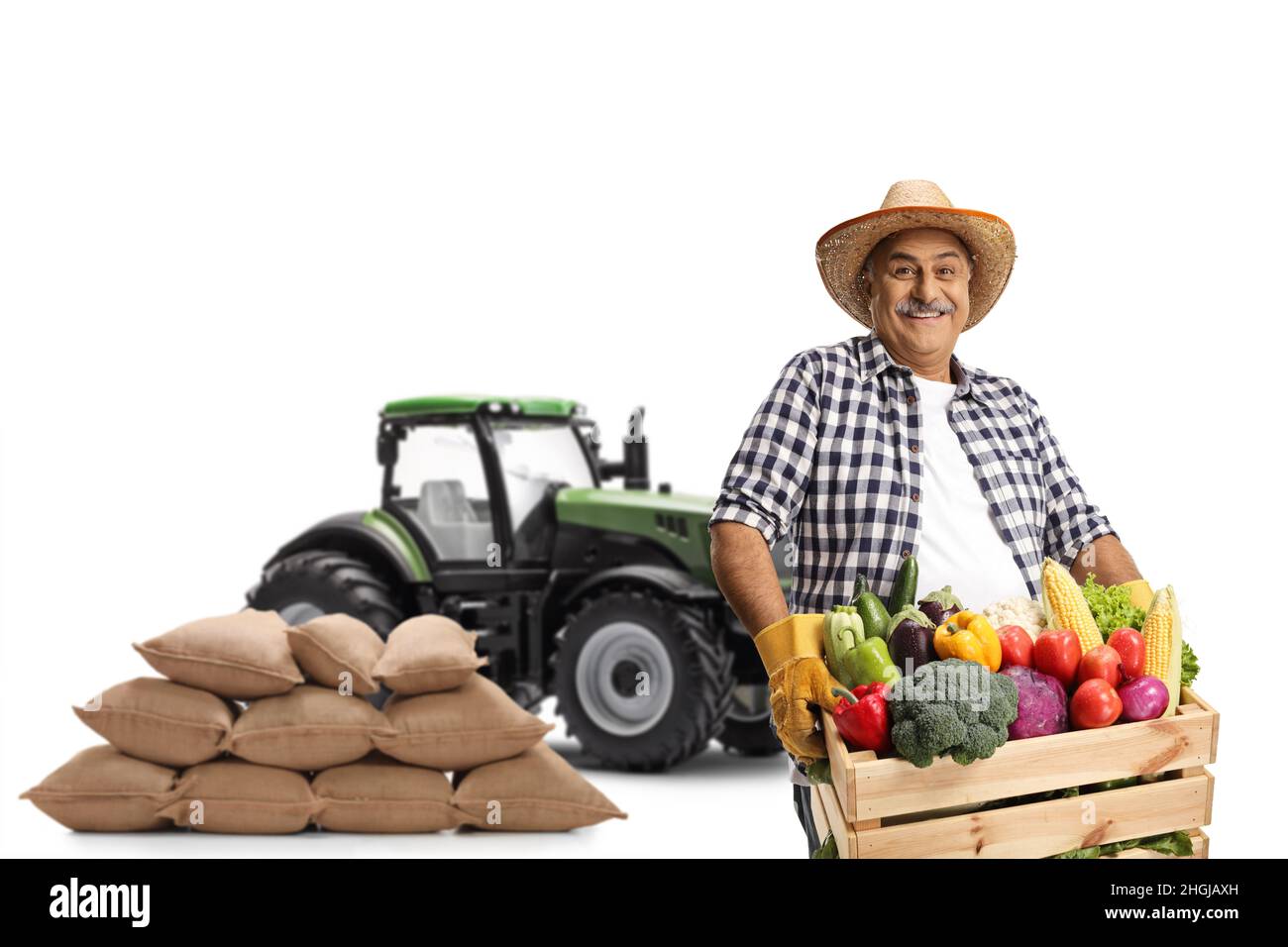 Mature farmer with a tractor carrying a crate full of organic ...