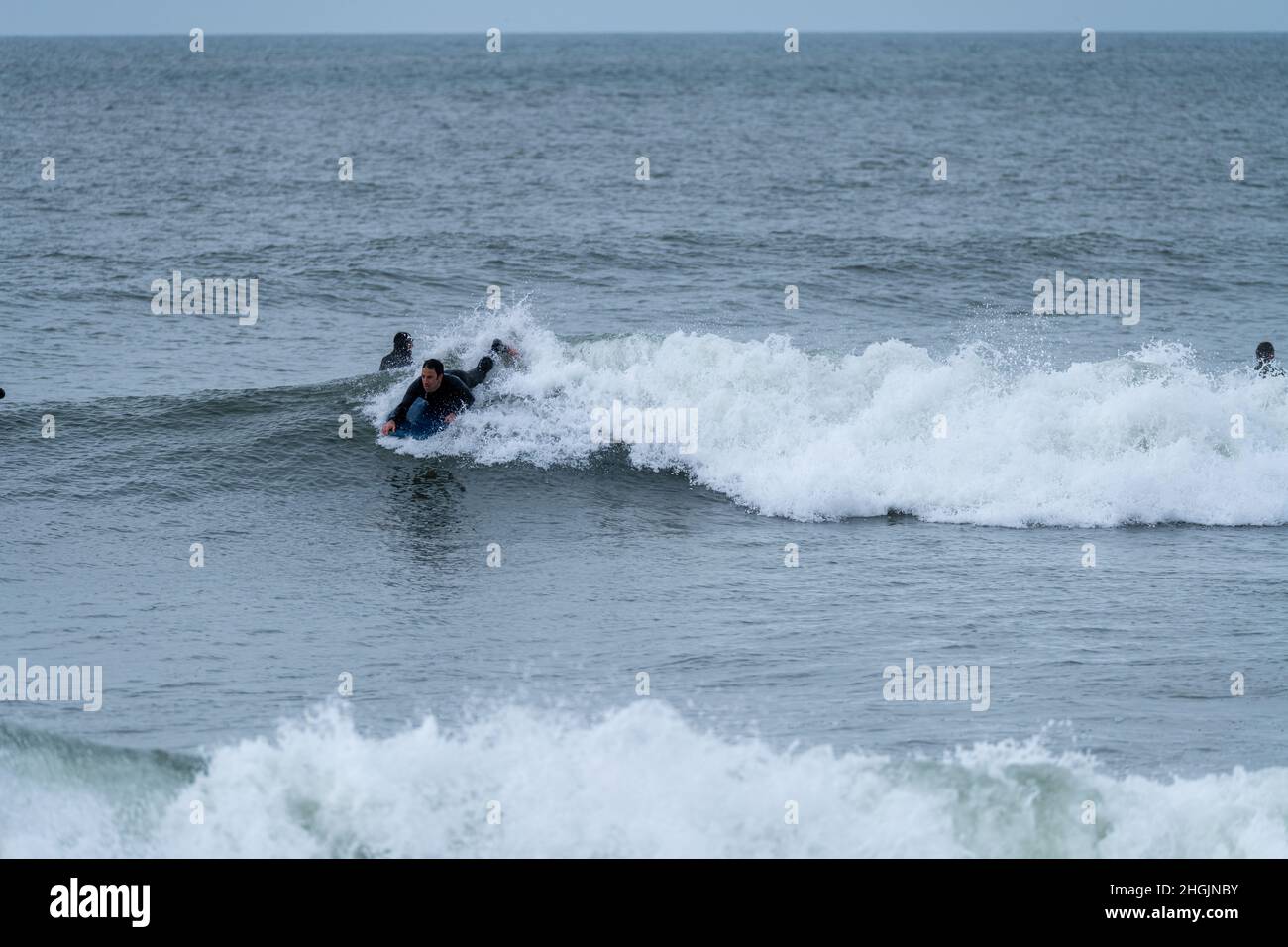 Ocean Wave Trick Roping Bodyboarder performing a 360 trick surfing ocean wave on a cloudy ...