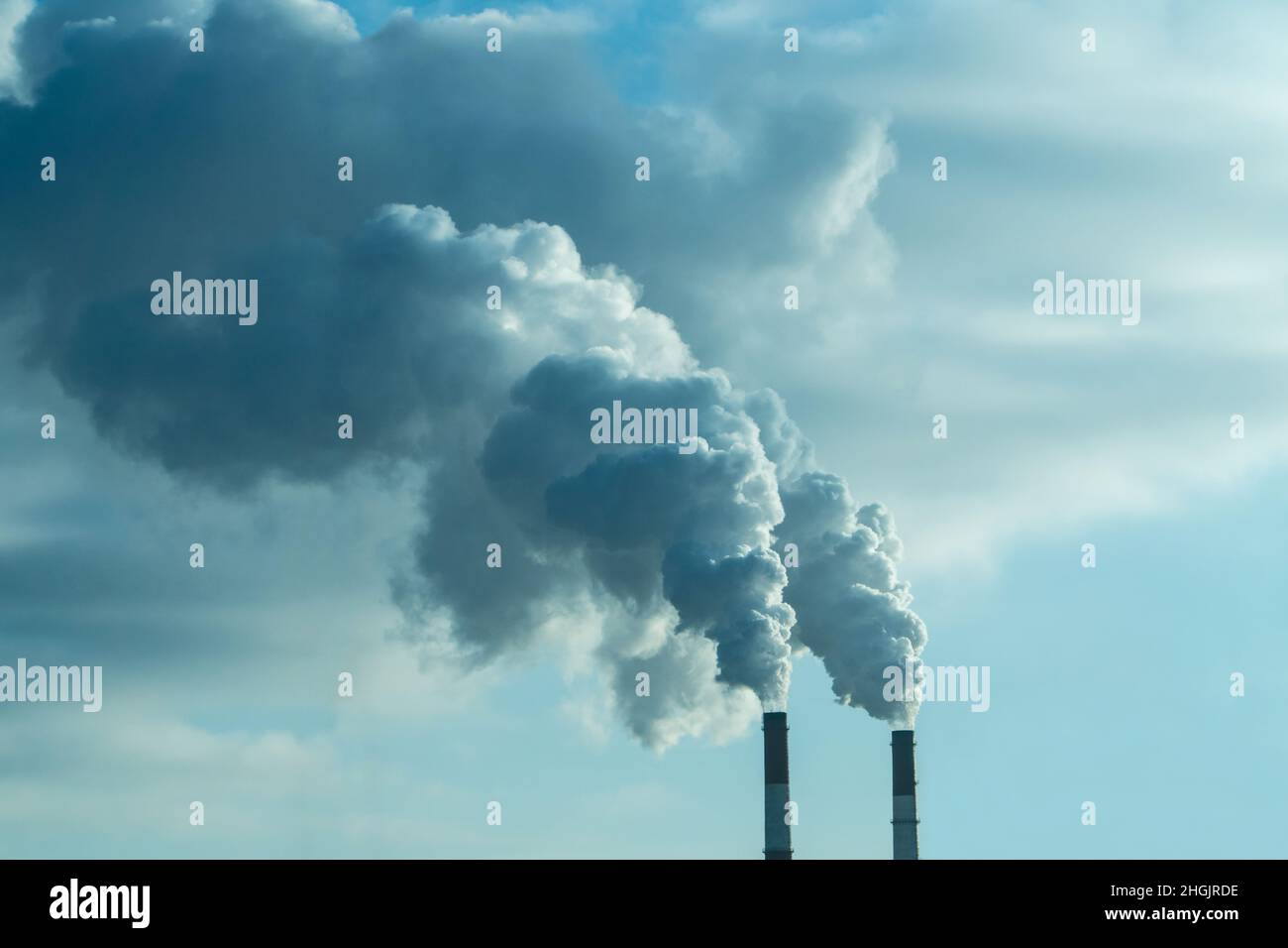 Steam coming out of pipes of thermoelectric power station in winter time. Termal power industry and environmental pollution concept and . Stock Photo