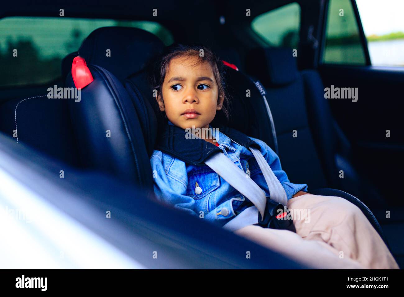 mixed race baby girl in car seat with fastened belt Stock Photo