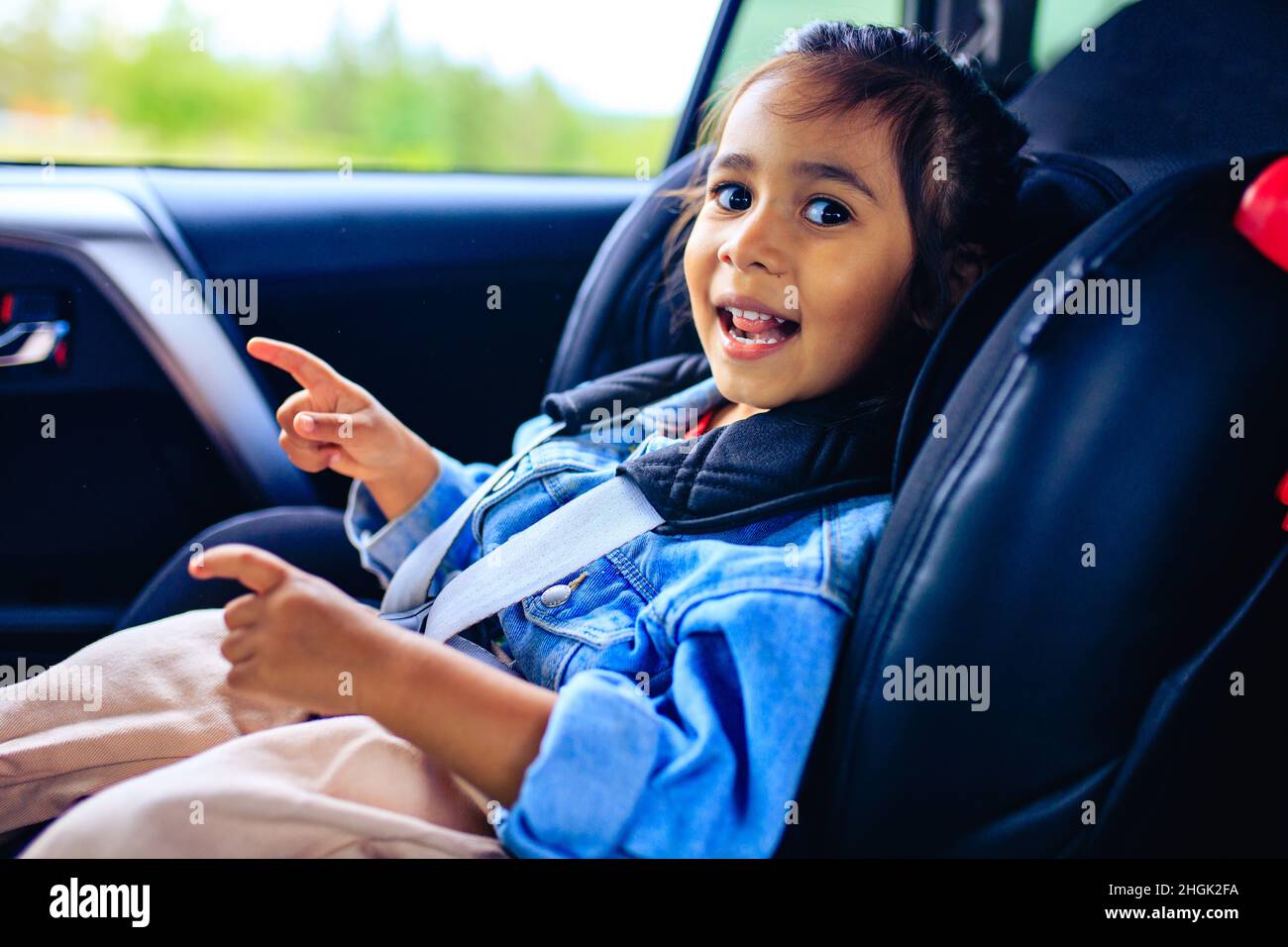 mixed race baby girl in car seat with fastened belt Stock Photo