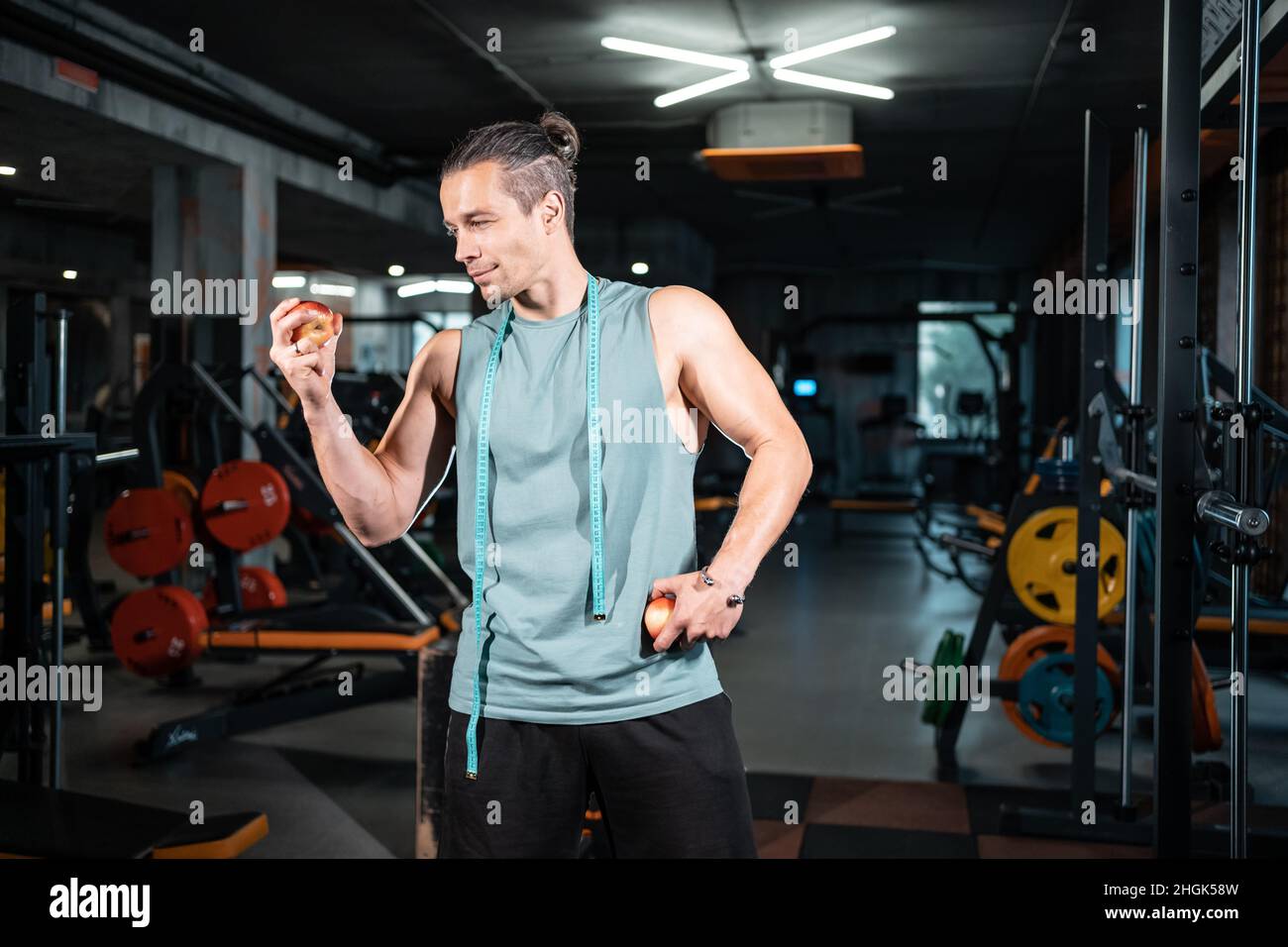 young handsome athlete hungry and eating healthy apple fruit in gym Stock Photo