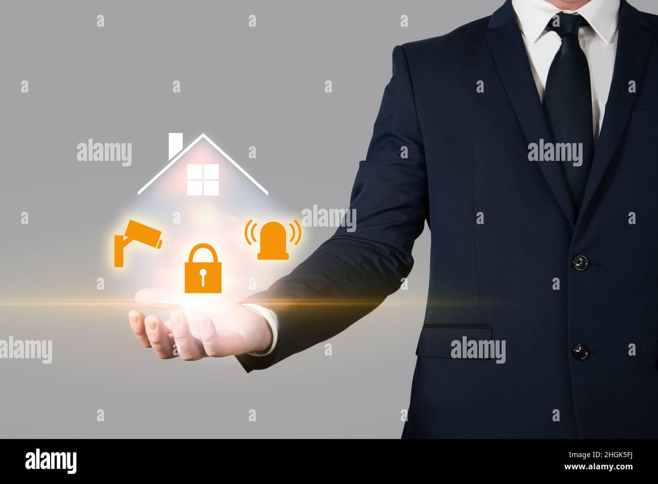 Insurance agent holding a house in the palm of his hand next to several security devices. Home insurance and burglary protection Stock Photo