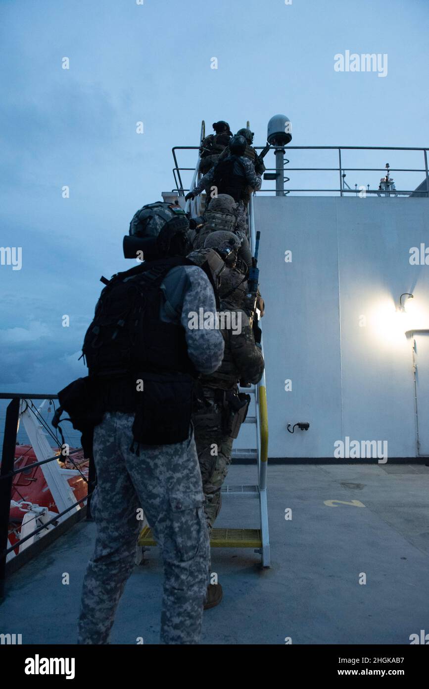 U.S. Naval Special Warfare operators and Indian Navy sailors move up a ladder well aboard USNS Pililaau (T-AK 304) during a helicopter assault force simulation as part of MALABAR 2021. MALABAR 2021 is an example of the enduring partnership between Australian, Indian, Japanese and American maritime forces, who routinely operate together in the Indo-Pacific, fostering a cooperative approach toward regional security and stability. NSW is the nation’s premiere maritime special operations force and is uniquely positioned to extend the Fleet’s reach and deliver all-domain options for naval and joint Stock Photo