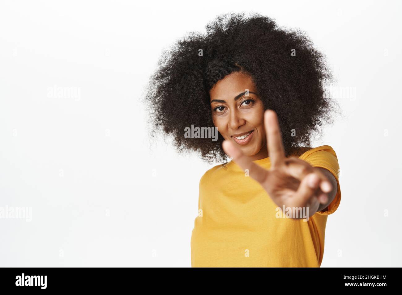 Positive and confident african woman shows v-sign, peace hand gesture ...